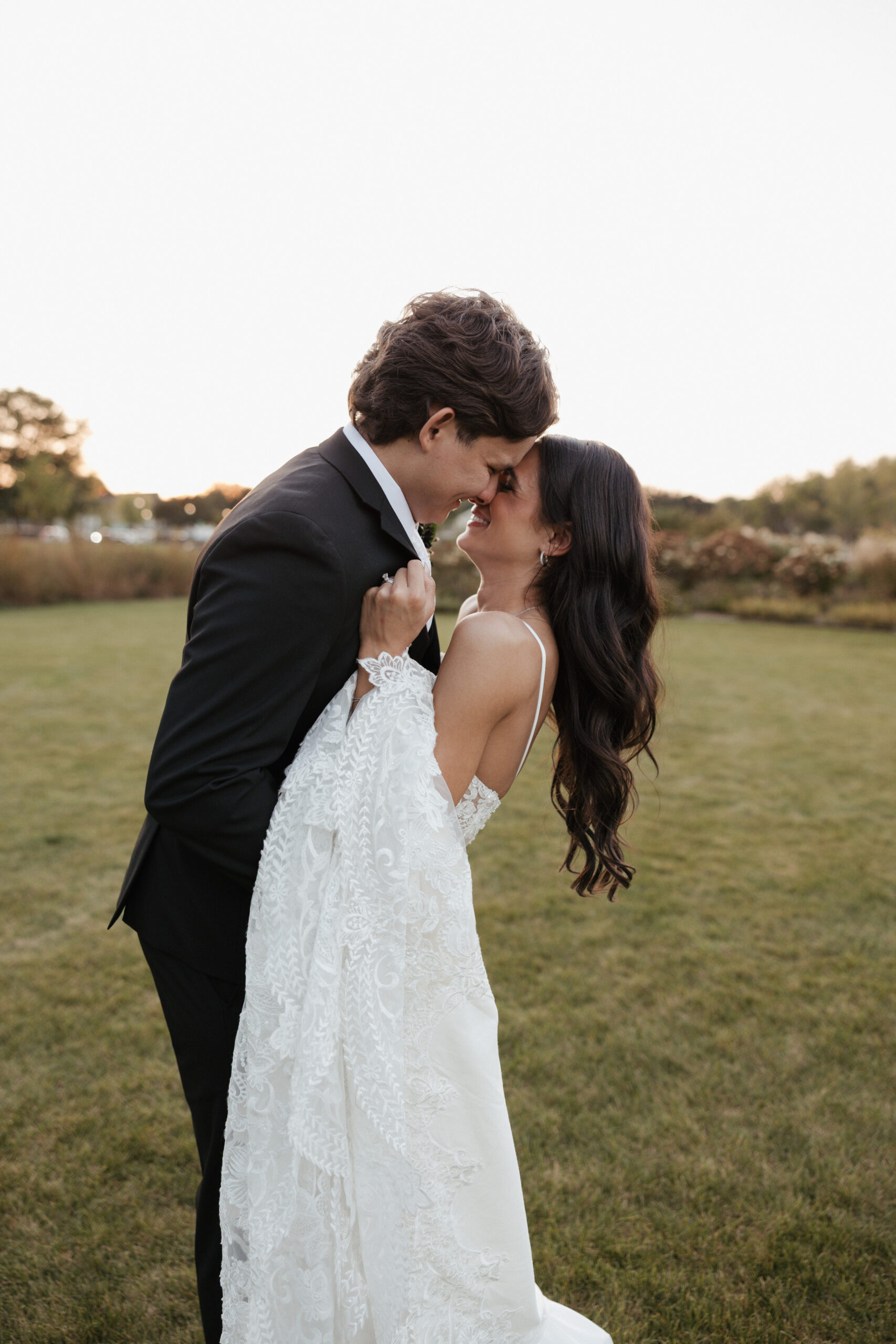 Bride and groom giggling while leaning in for a kiss