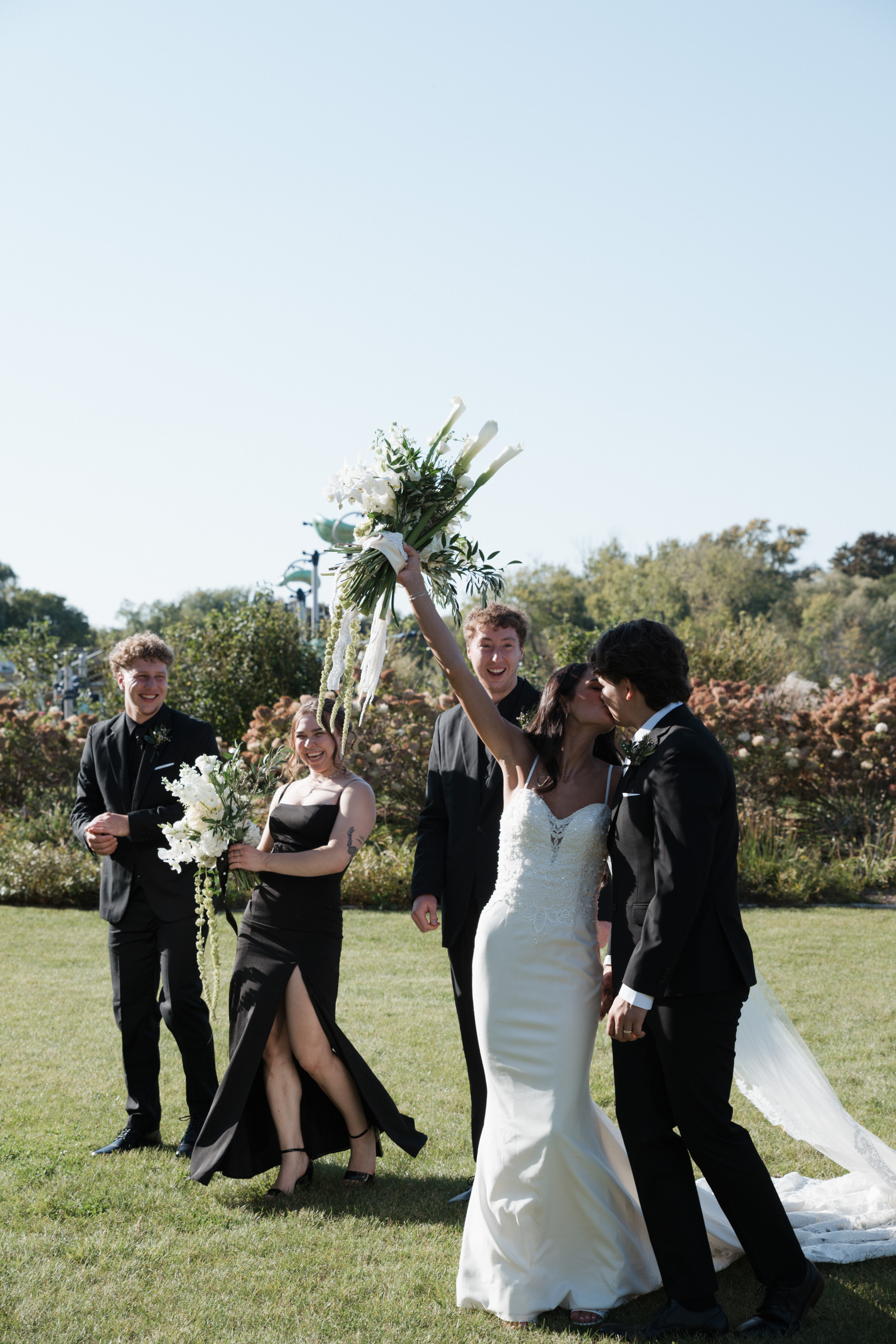 Bride and groom kissing while walking across a lawn with their wedding party
