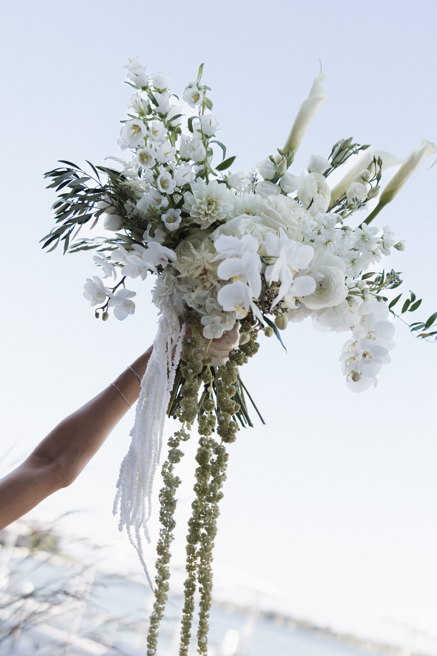 White wedding bouquet being held up in the air for a wedding photo