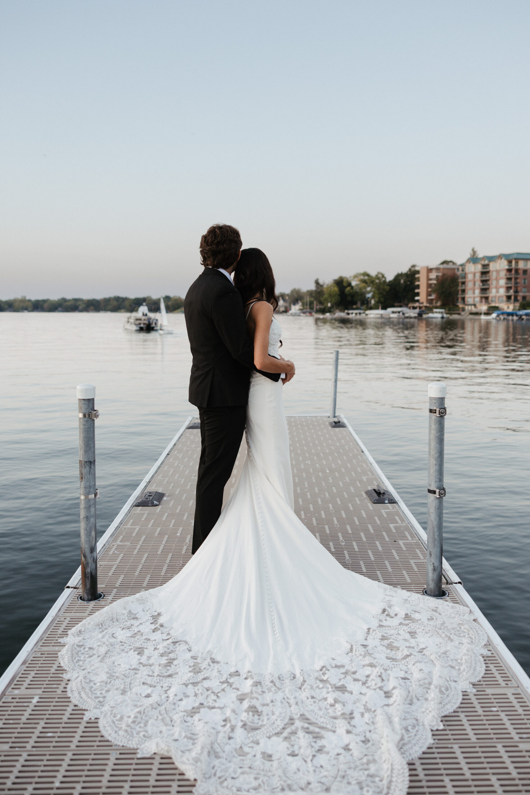 Bride and groom posing on a boat dock looking out at the water