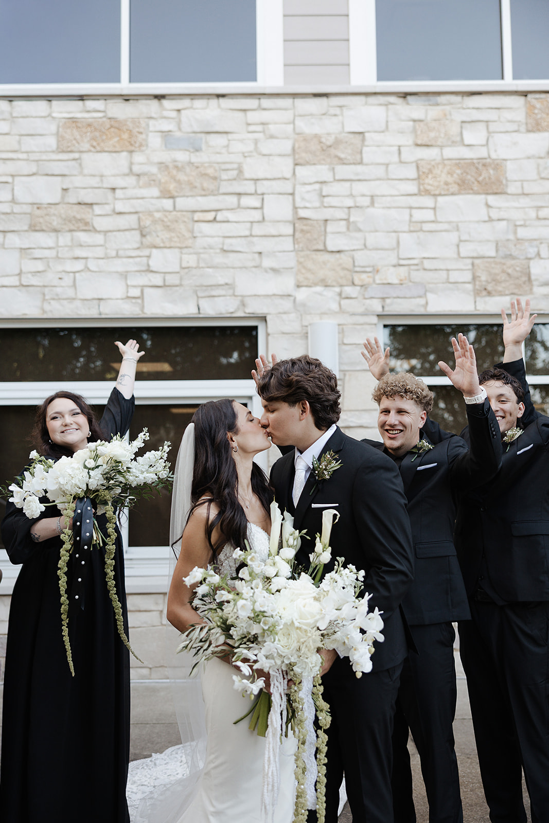 Bride and groom kissing in between bridal party cheering