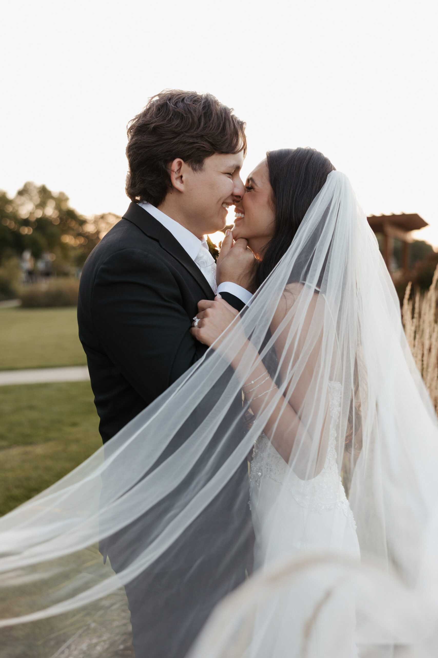 Bride and groom laughing while leaning in for a kiss