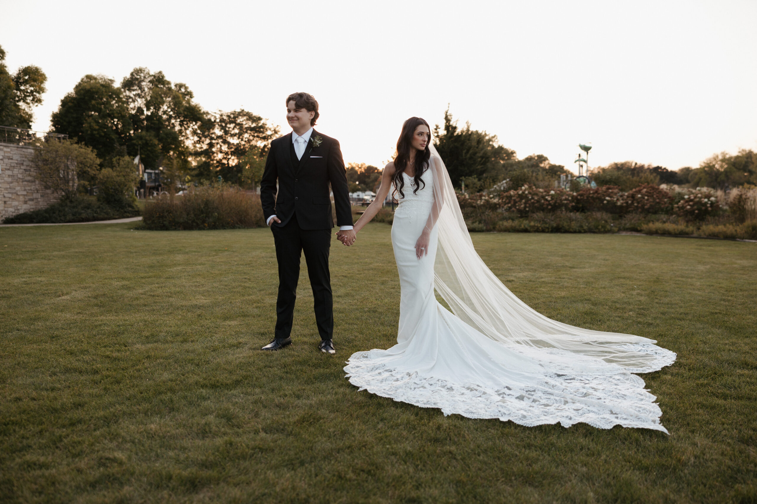 Bride and groom holding hands and looking opposite directions in sunset wedding photos