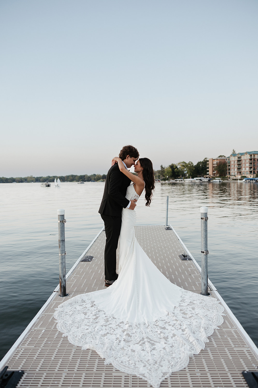 Bride and groom posing on a boat dock looking out at the water