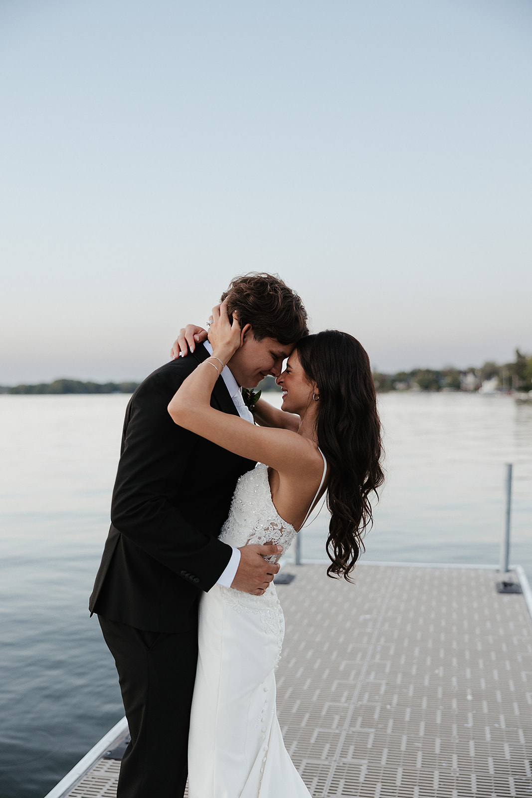 Bride and groom posing on a boat dock looking out at the water