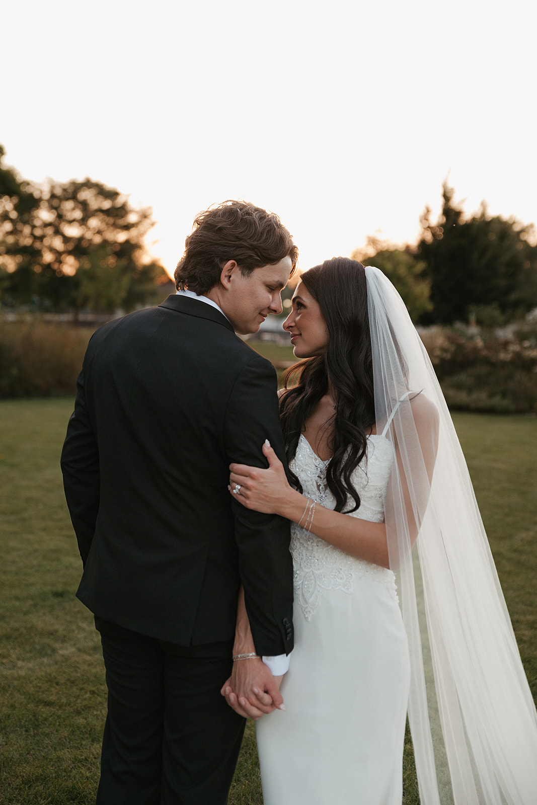 Bride and groom smiling at each other during sunset wedding photos