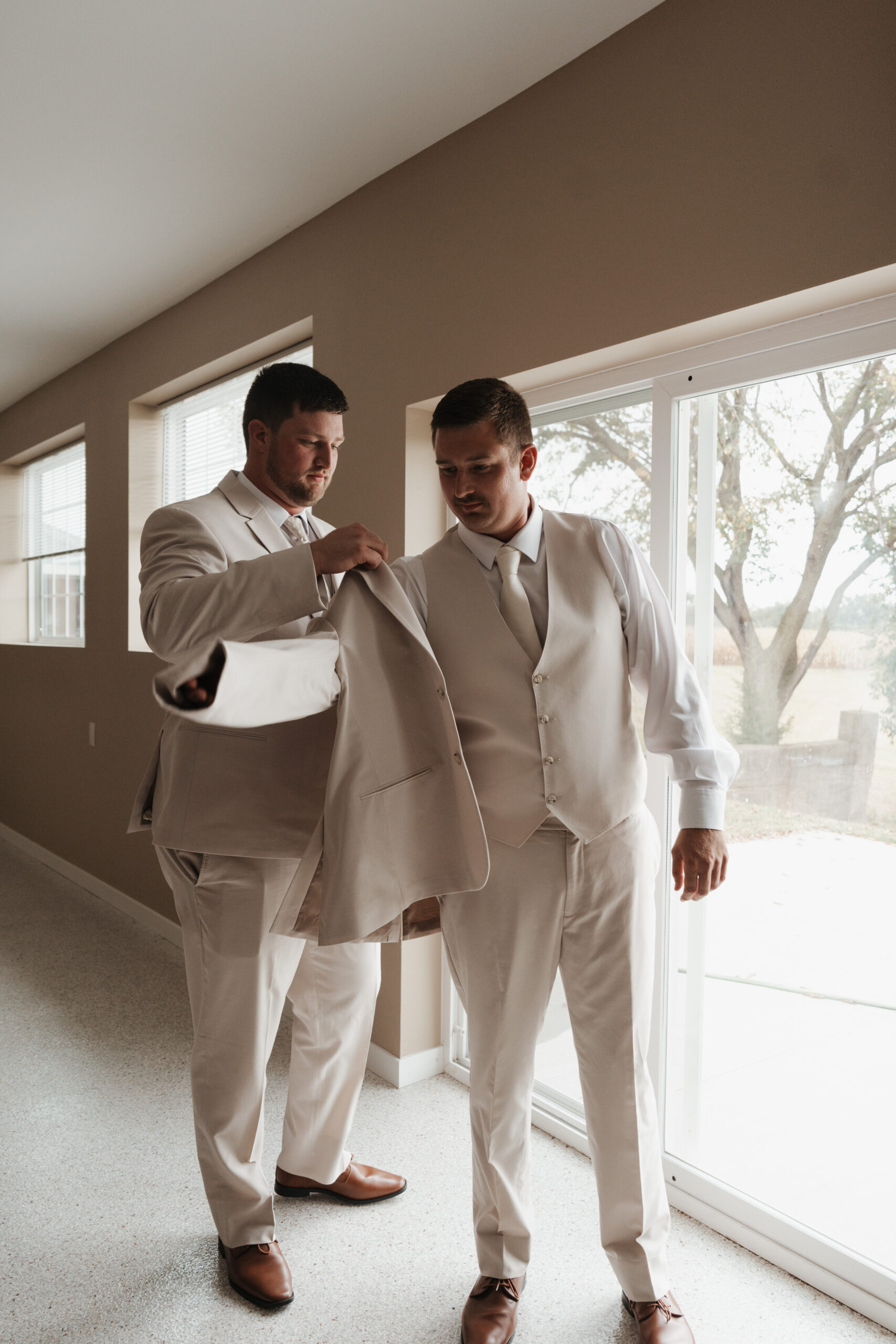 A groom during getting ready photos putting on his jacket