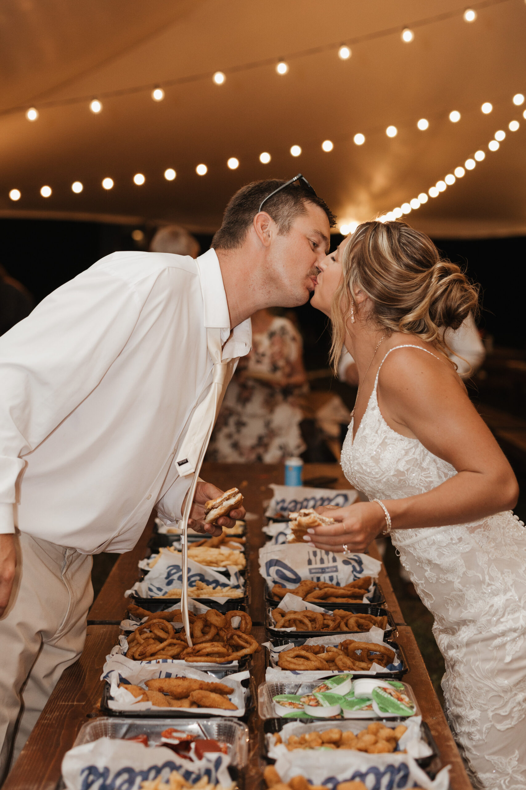 A bride and groom kissing over Culver's, which they got catered as a late-night snack for their wedding reception