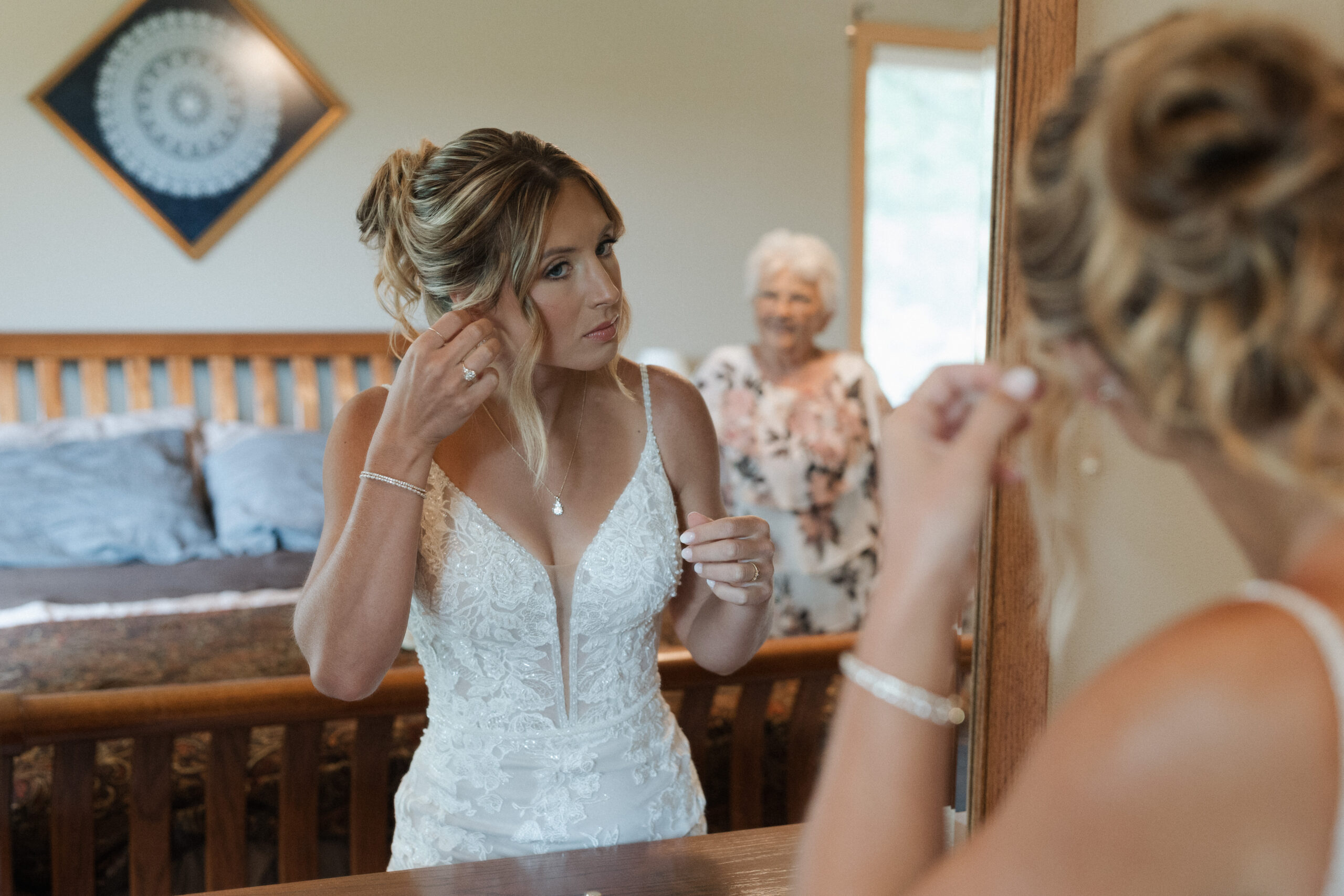 A bride getting ready for her backyard wedding while her grandmother watches her in the mirror