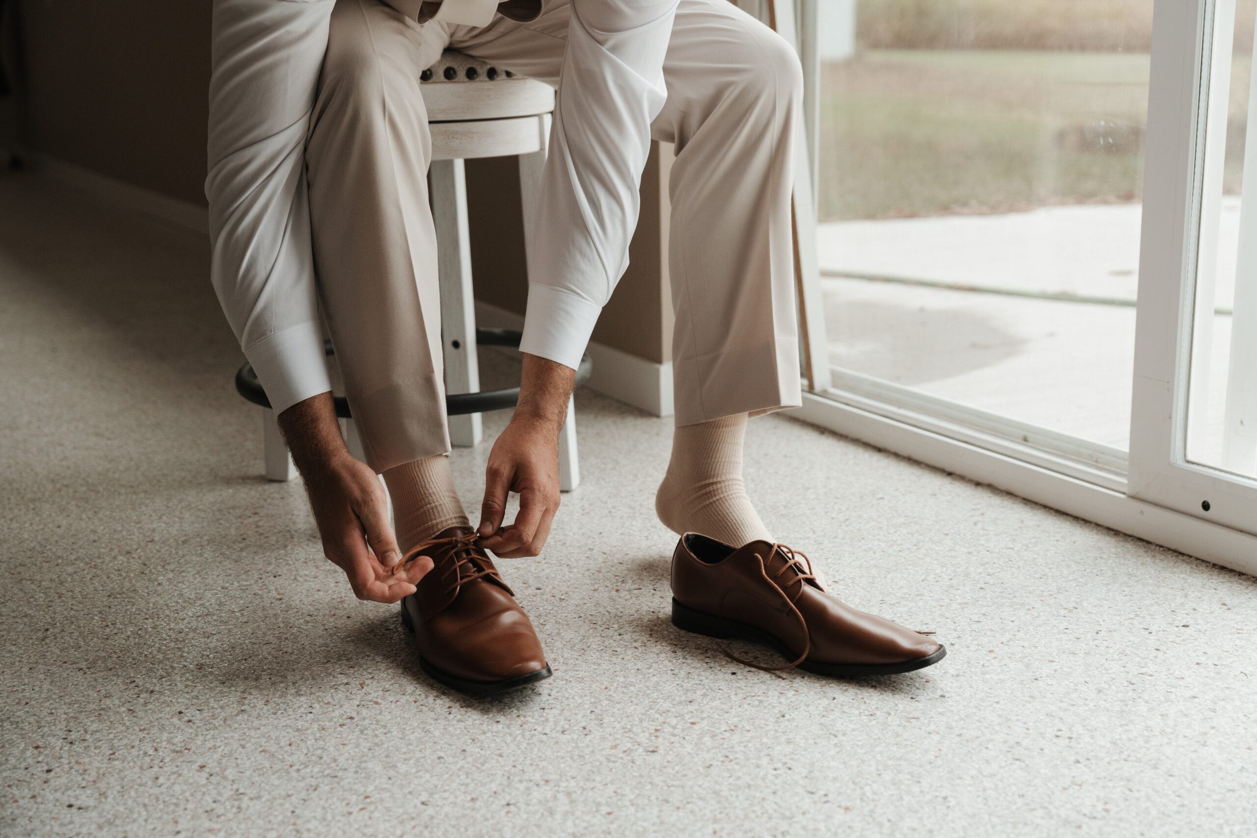 A groom putting on his shoes before his wedding