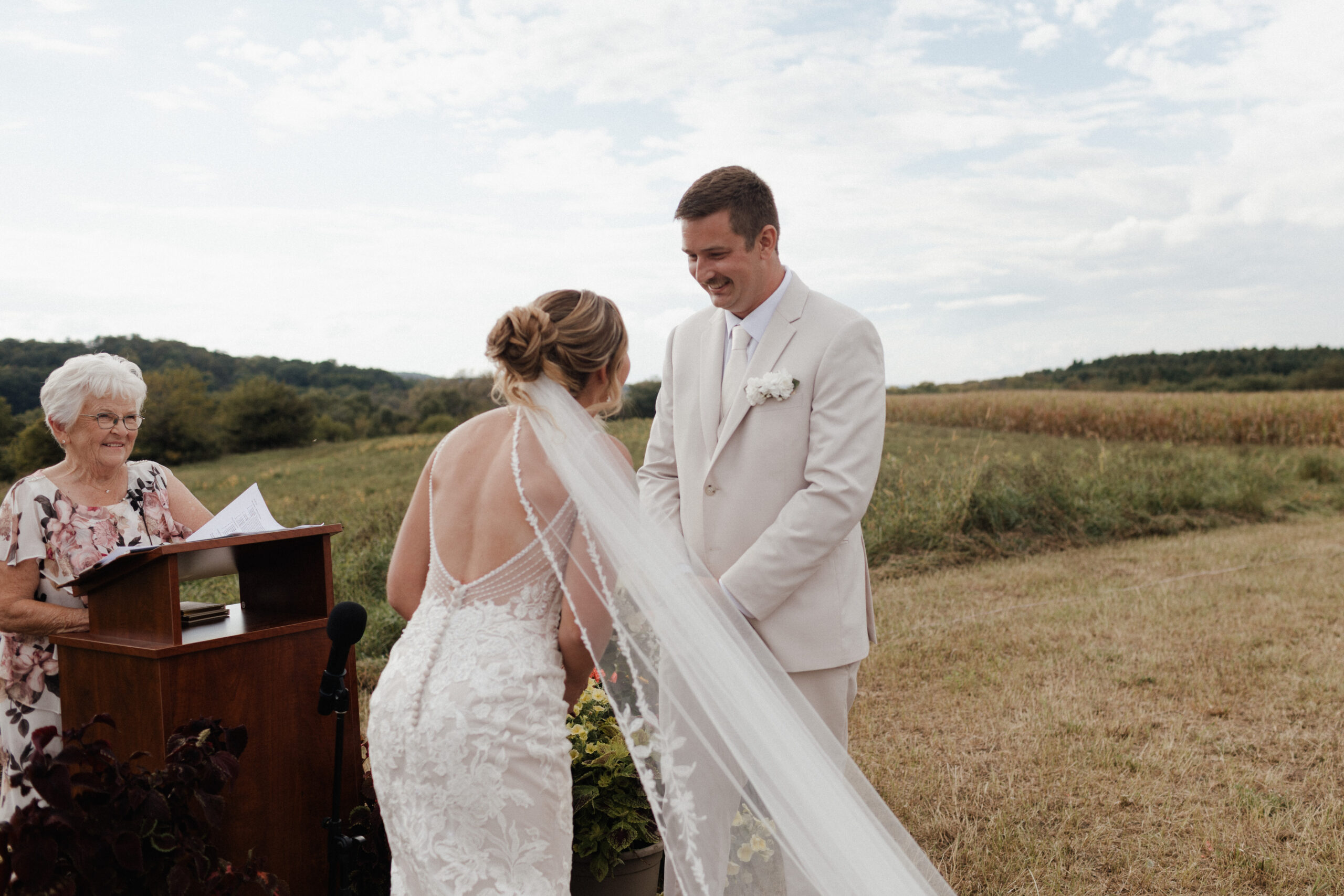 A groom laughing seeing his bride for the first time during a backyard wedding ceremony