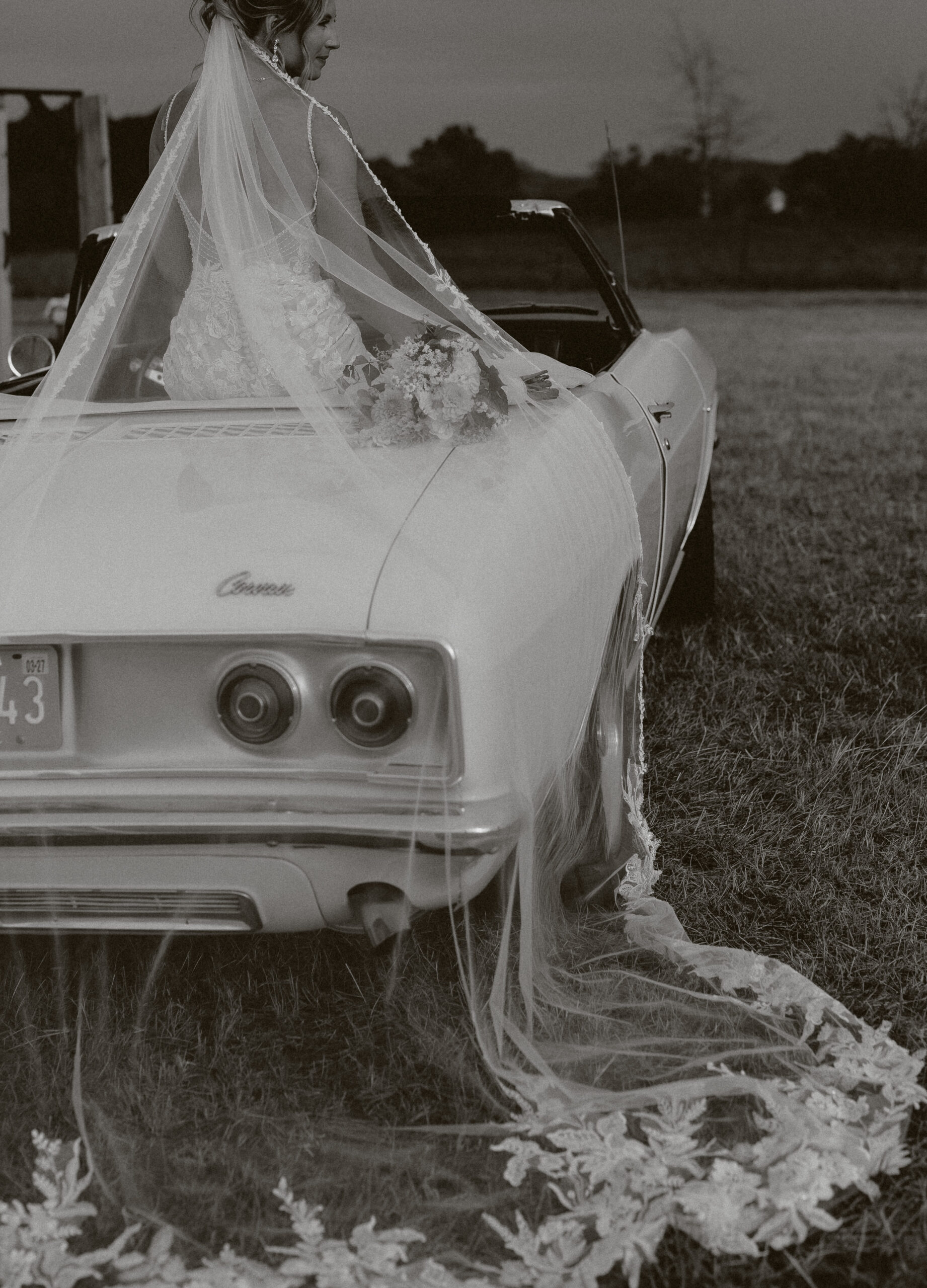 A bride riding into her backyard wedding ceremony on a vintage car