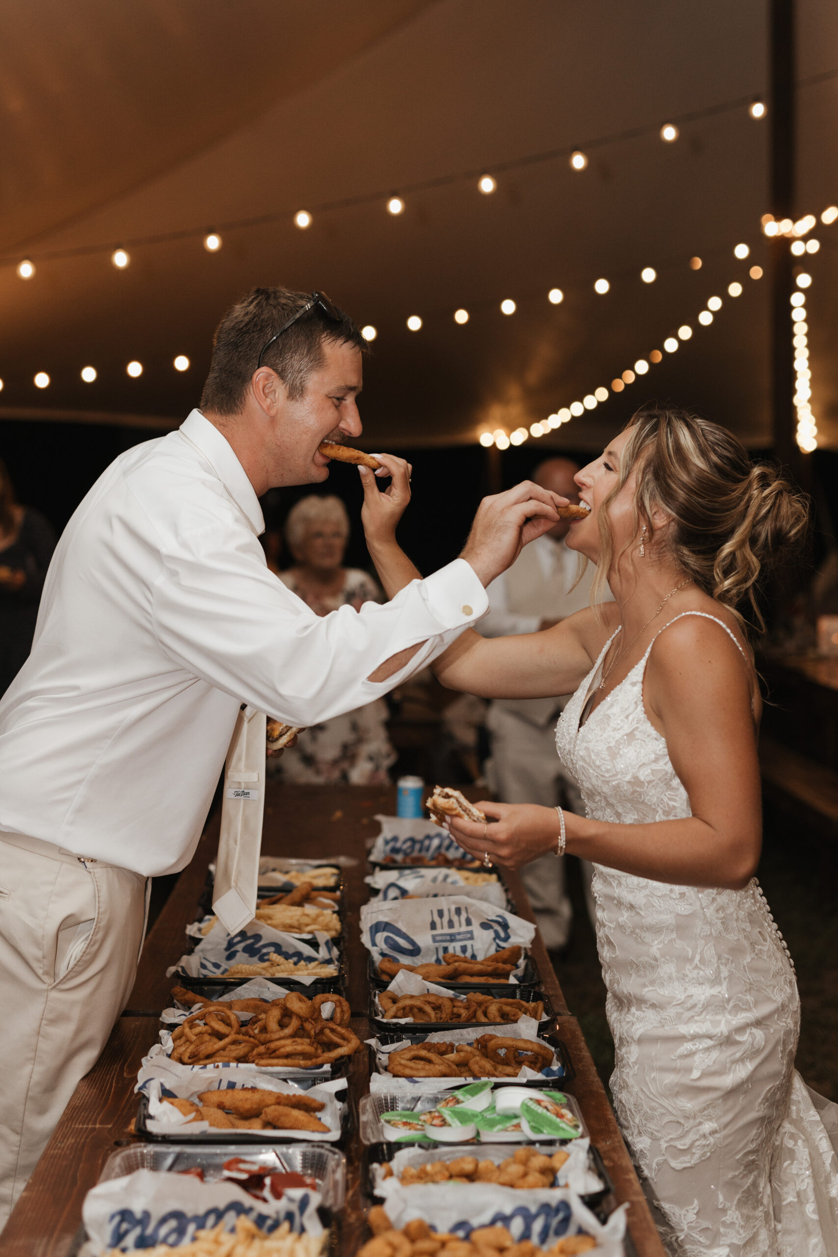 A couple feeding each other Culver's, who catered their late night snack at their backyard wedding