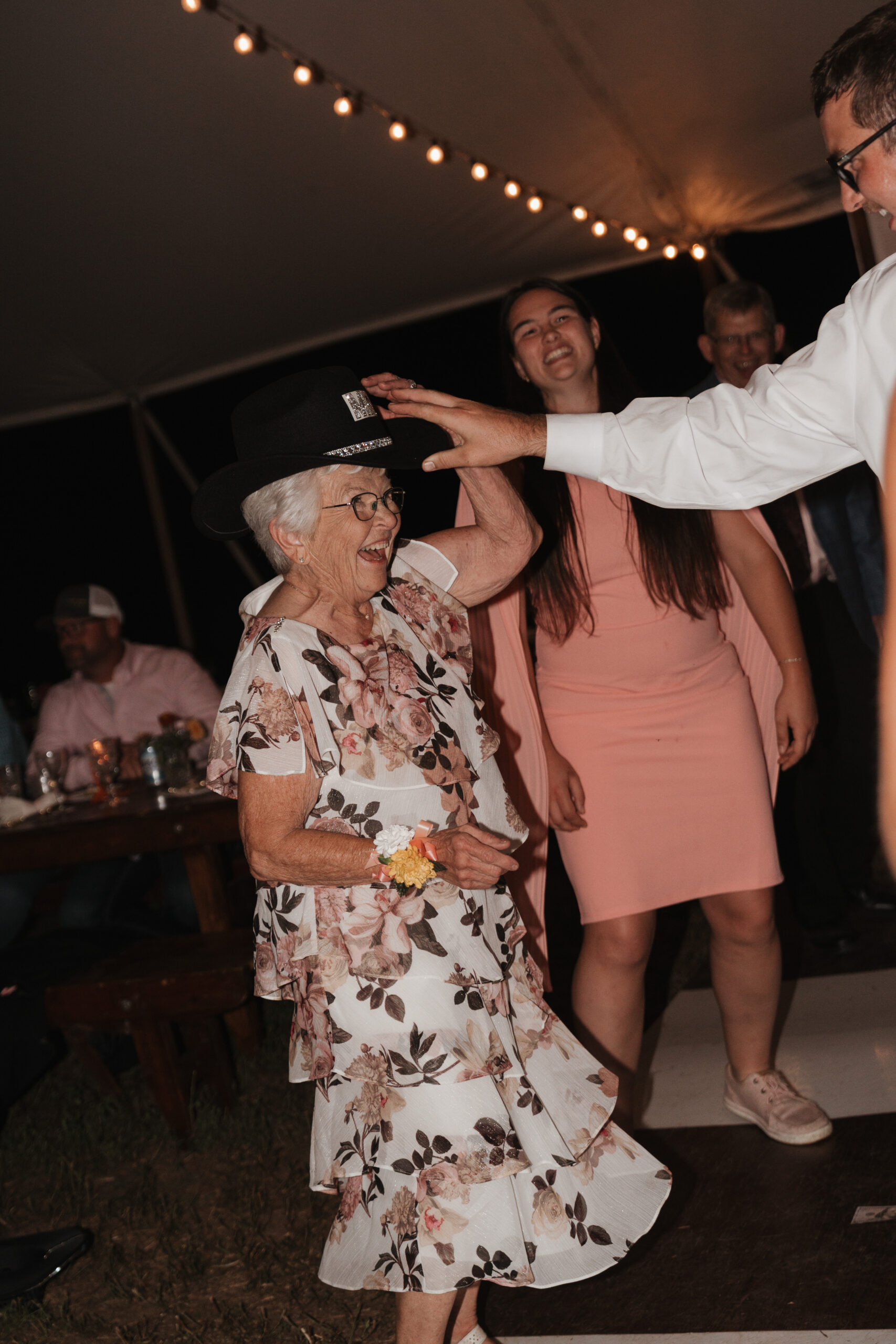A grandmother wearing the groom's cowboy hat on a wedding dance floor
