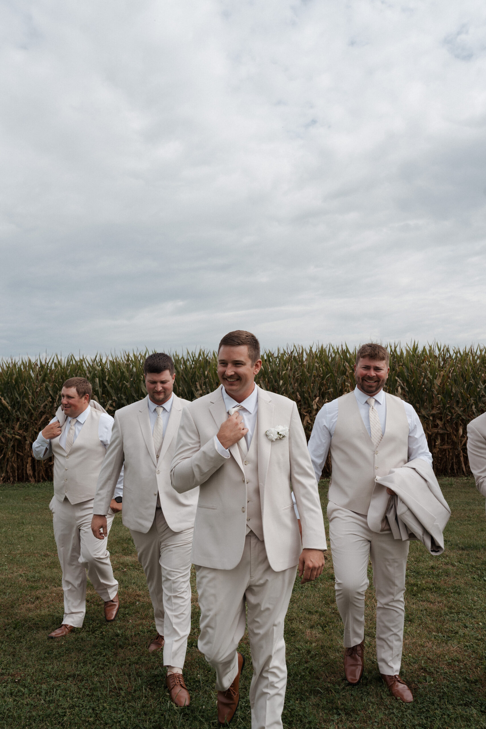 Groom and groomsmen walking towards the camera at a backyard wedding
