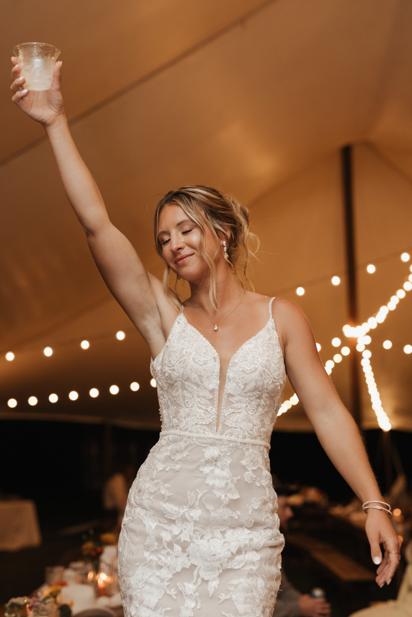 A candid photo of a bride holding her drink up during her wedding reception