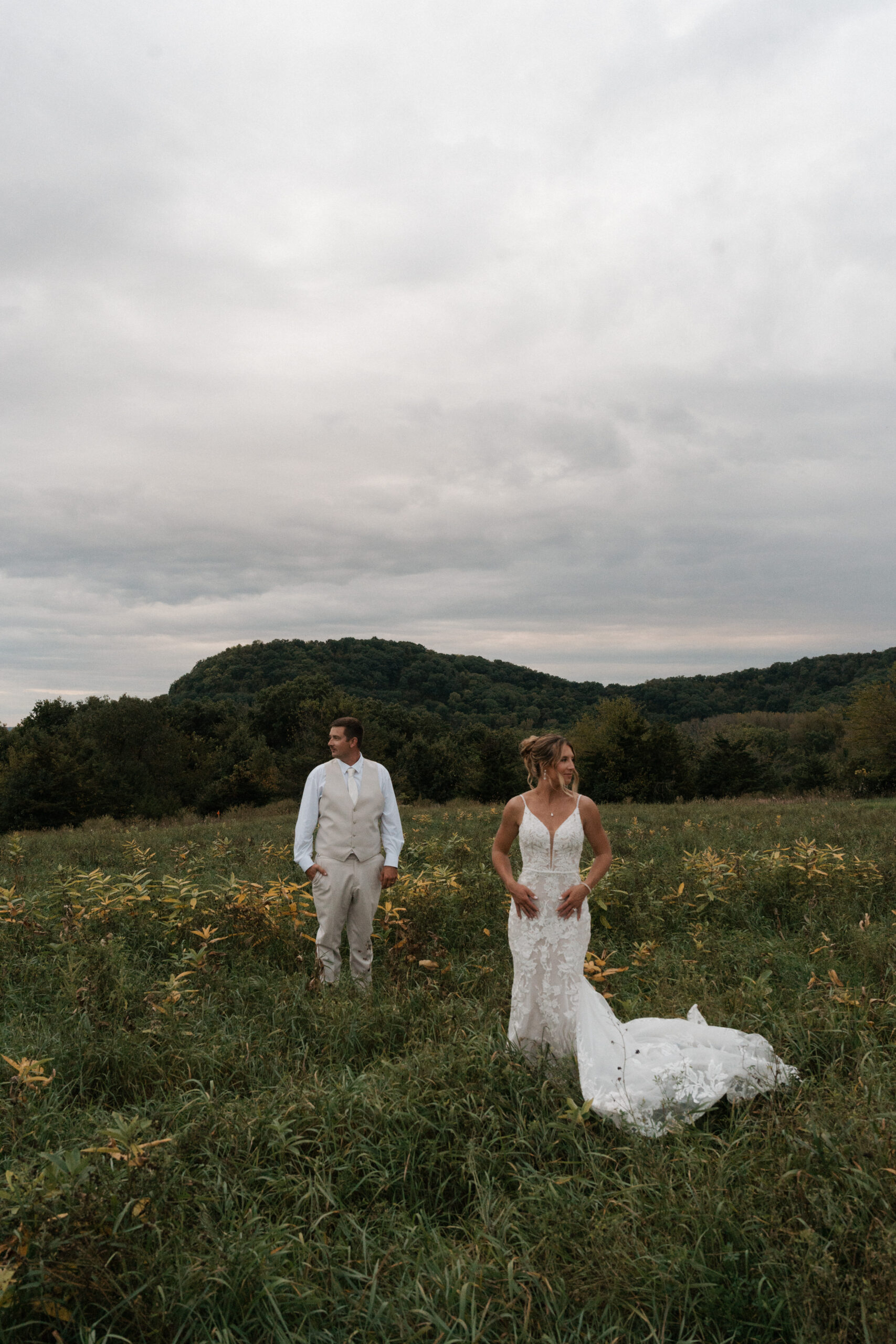 A bride and groom posing for an editorial wedding photo in front of a mountain at their backyard wedding
