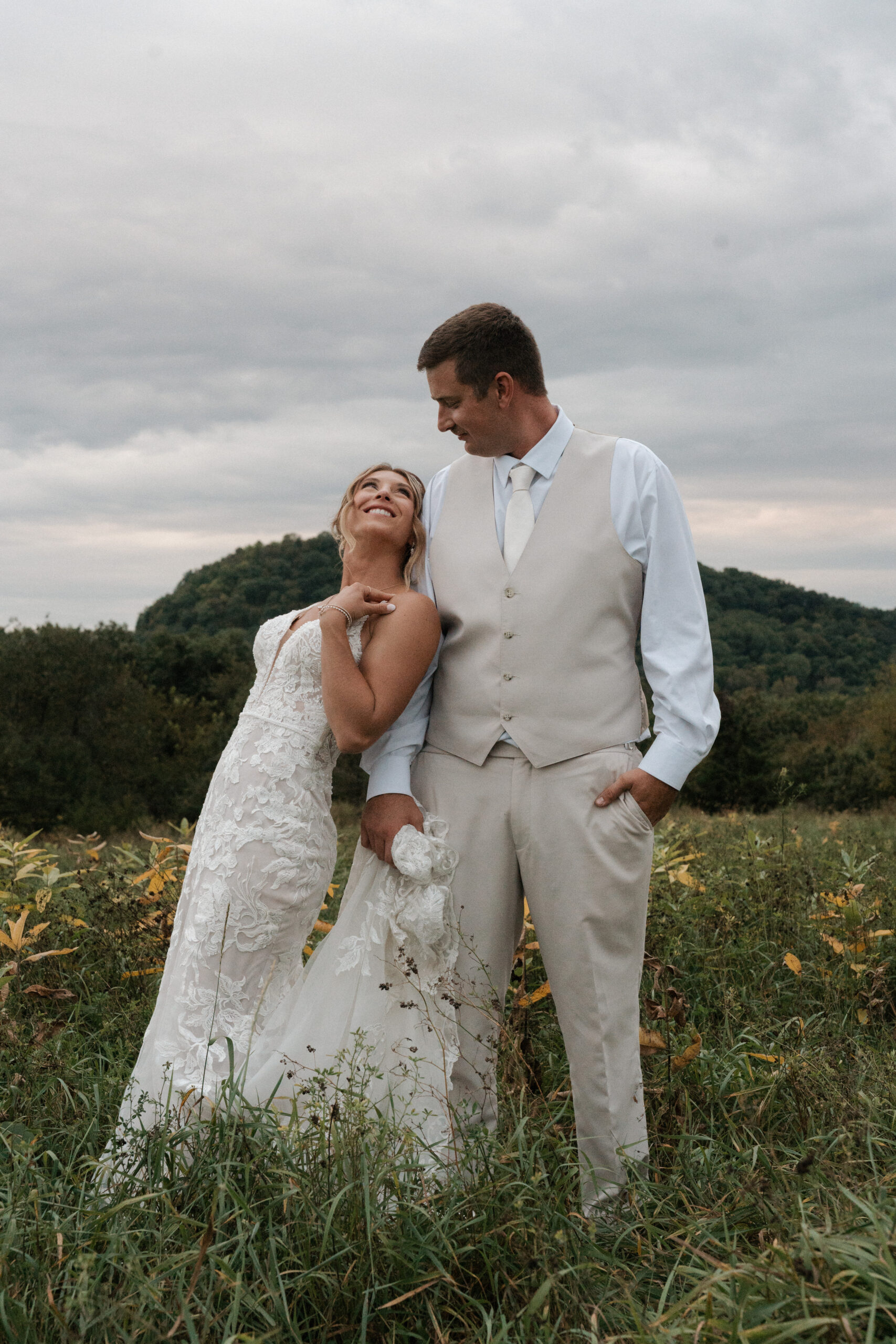 A bride leaning against a groom smiling at him at their backyard wedding
