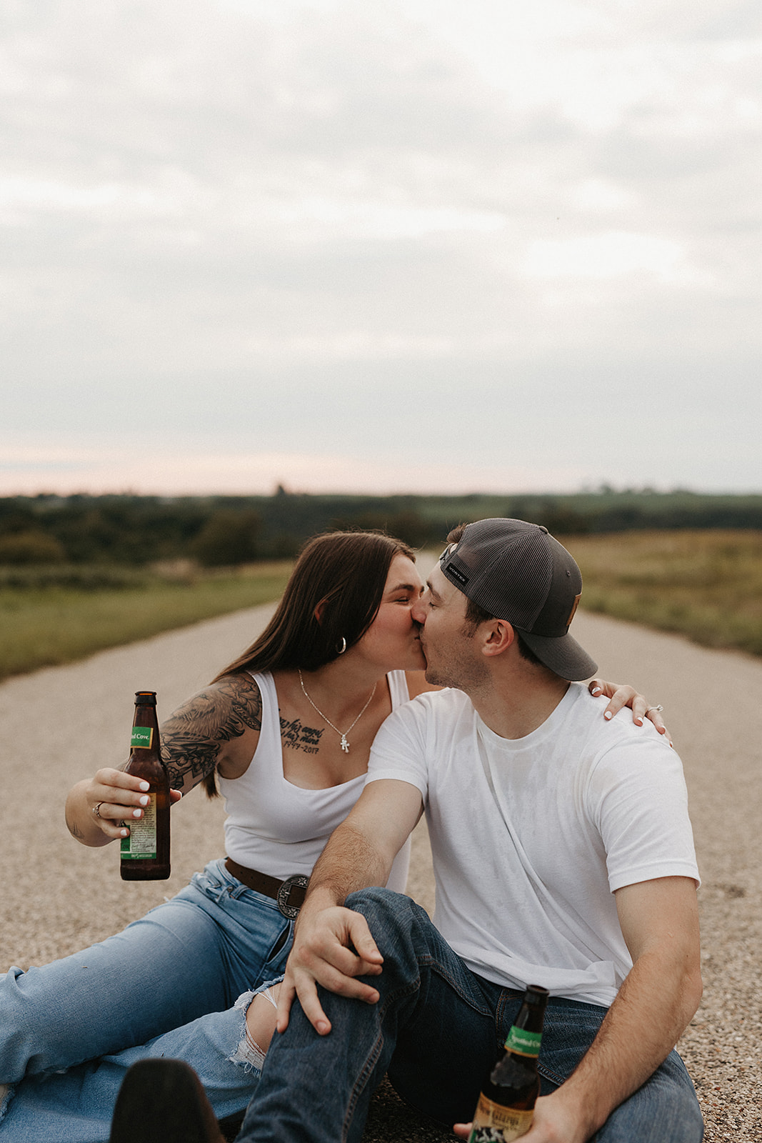 A couple kissing on the street holding beer, as an engagement photo ideas