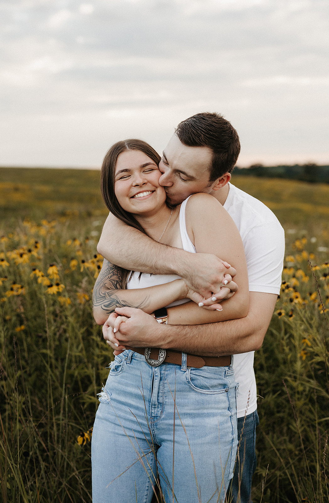 A man kissing his fiancee on the cheek showing engagement photo ideas