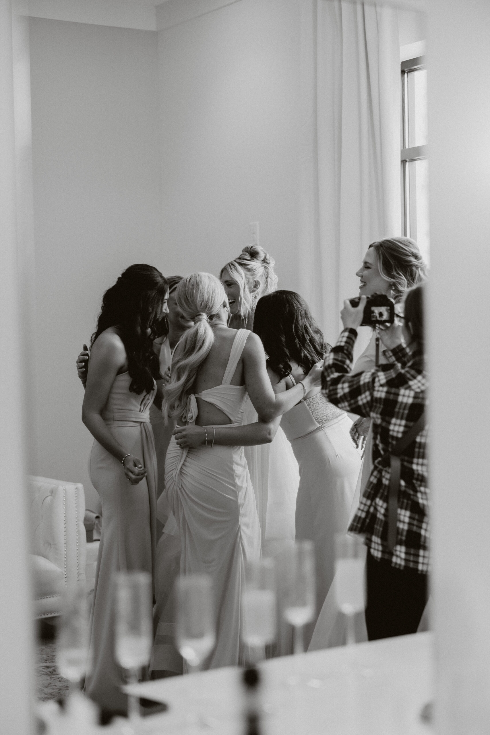 A candid wedding photo of bridesmaids hugging a bride during getting ready photos
