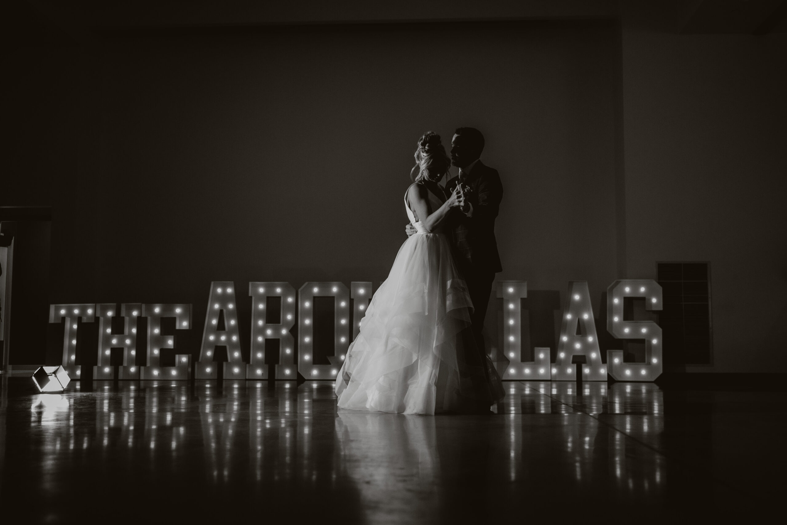 A wedding couple dancing in front of marquee letters of their last name at their wedding reception
