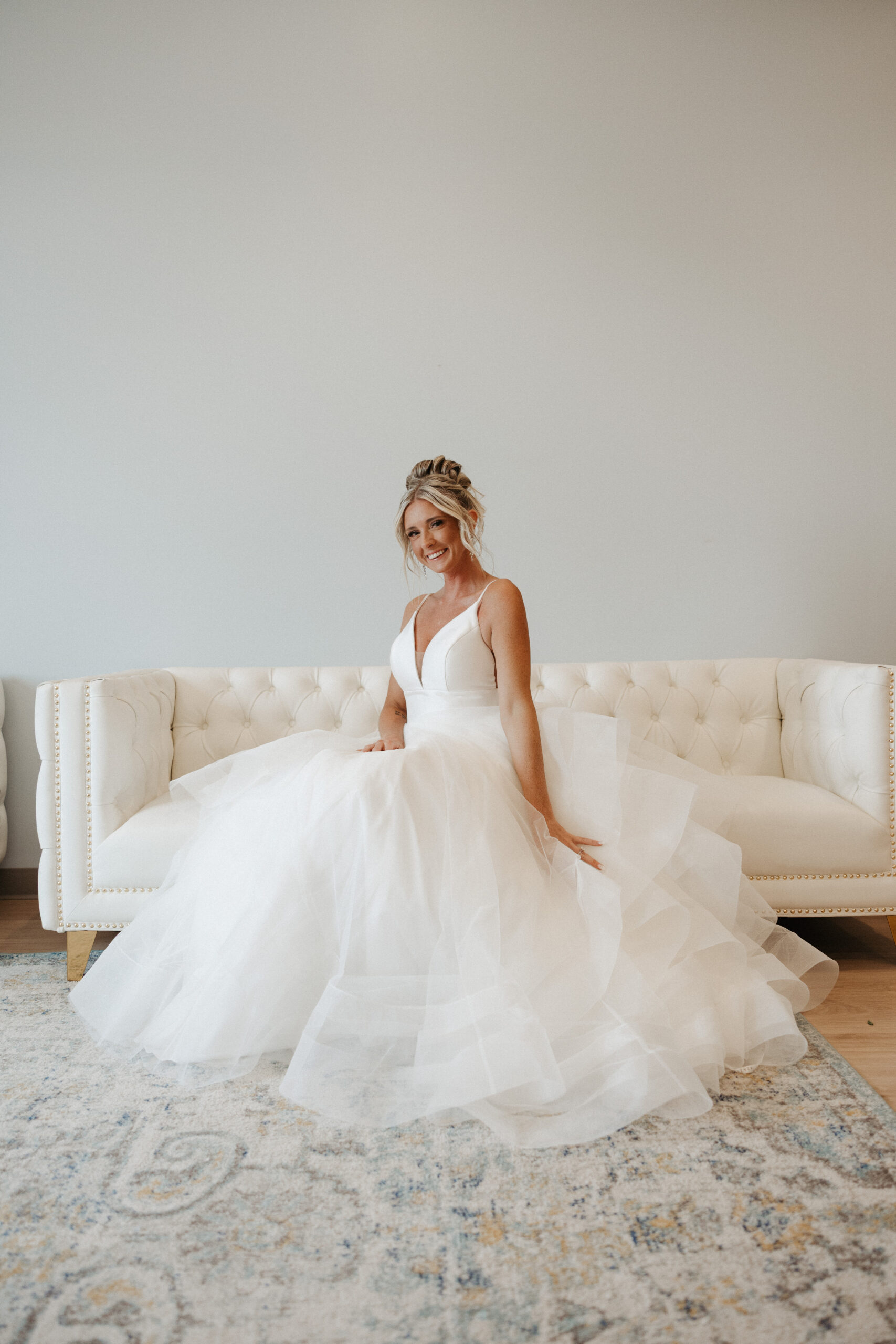 A bride posing for bridal portraits on the couch in the getting ready suite in the valerie