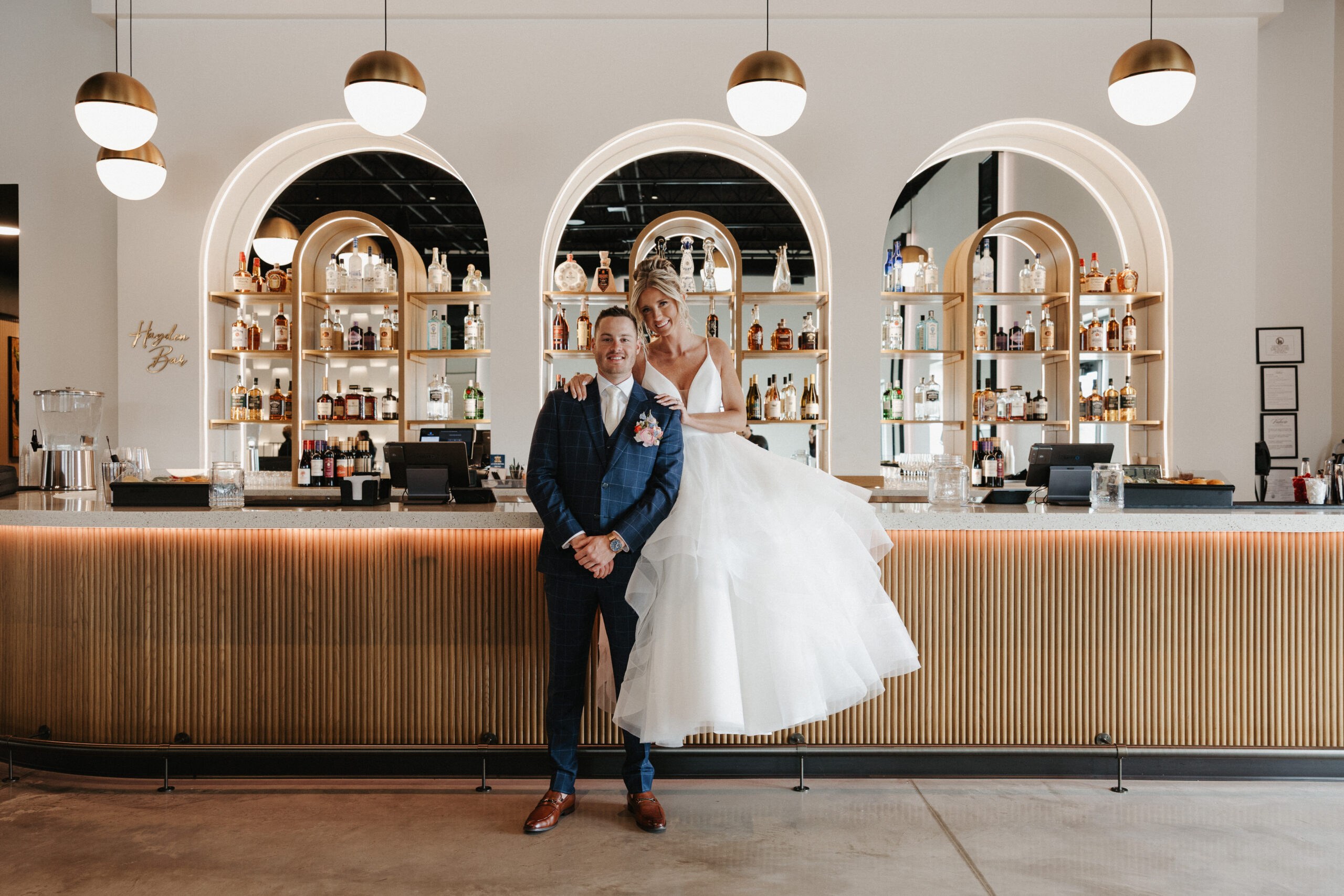 A couple sitting on the bar for wedding photos at The Valerie