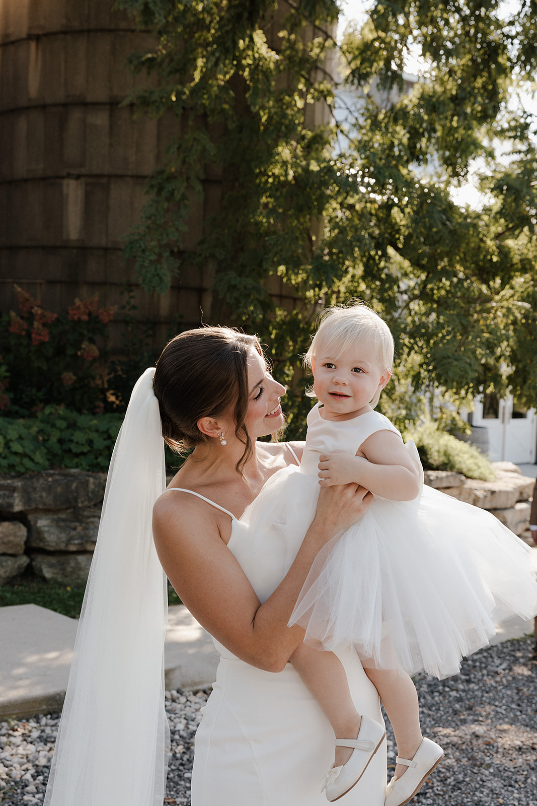 A bride holding a flower girl in a candid wedding photo in a wedding blog post answering the question "how much does wedding photography cost?"