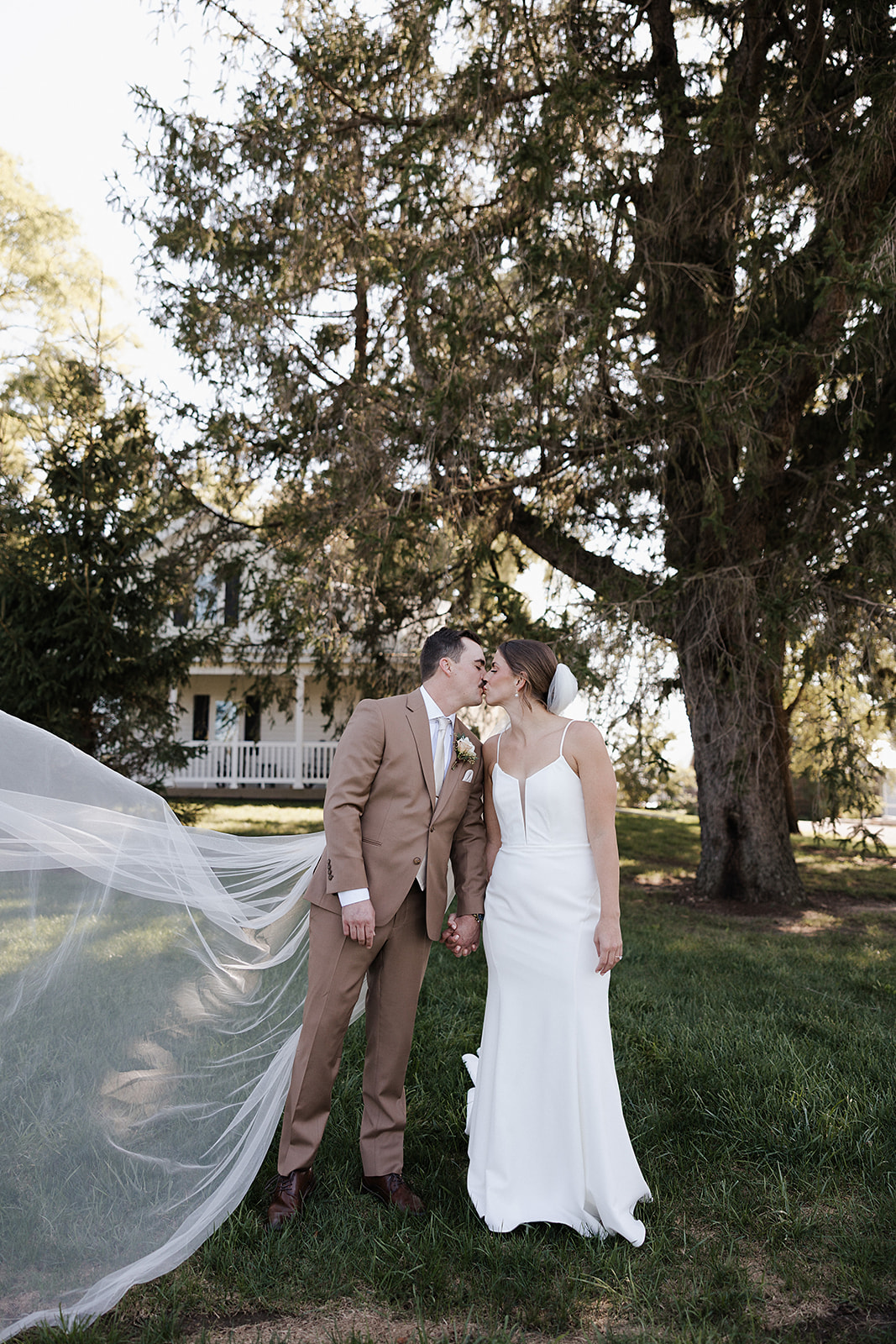A bride and groom kissing with the bride's veil blowing in the wind, captured by a Wisconsin wedding photographer