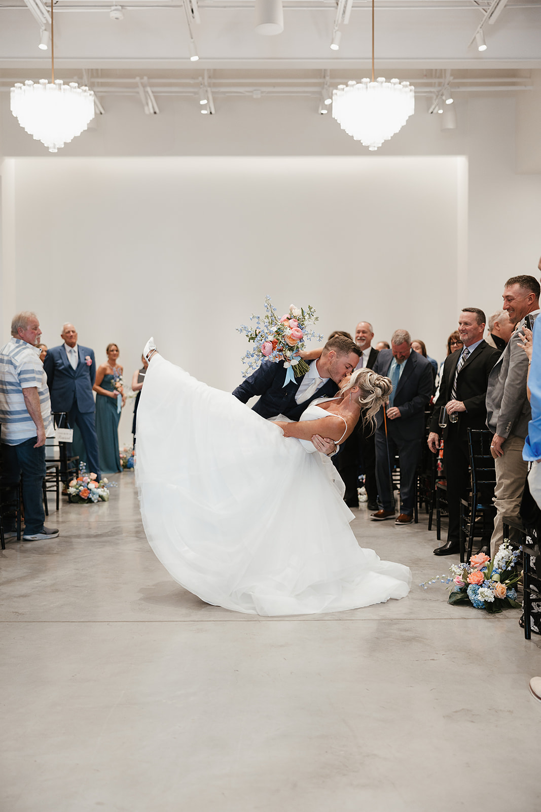 A bride and groom kissing while exiting A wedding ceremony inside a Wisconsin wedding venue, the Valerie