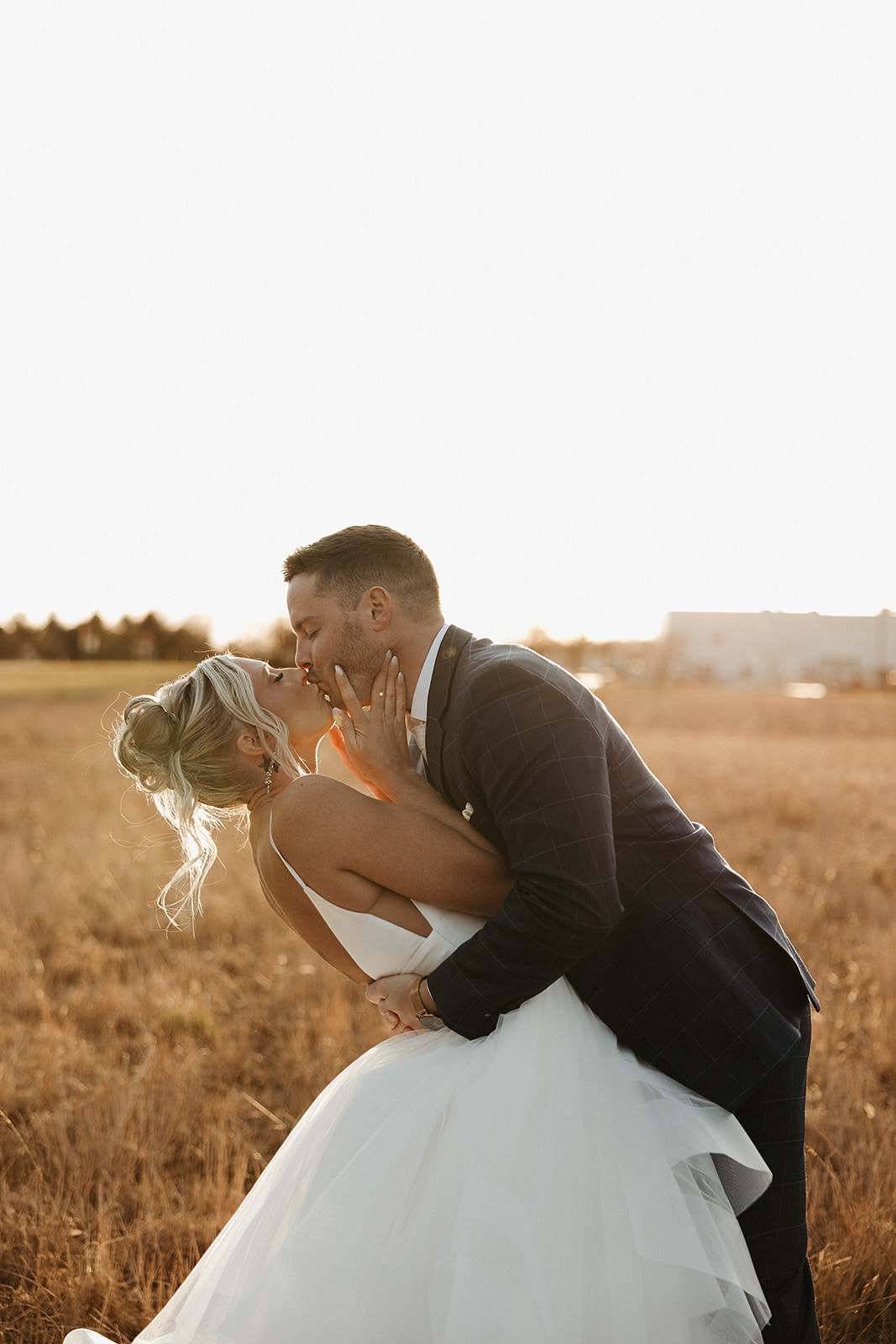 A bride and groom kissing in a field at the valerie