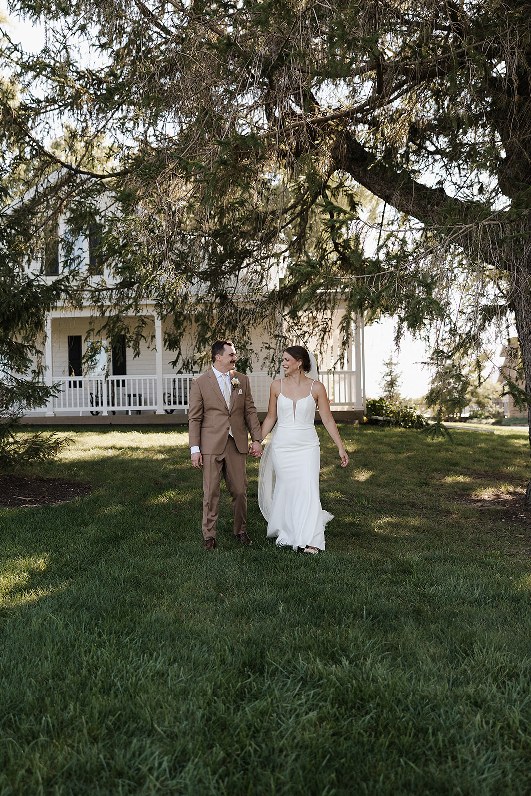 A bride and groom walking in a field in front of lilac acres