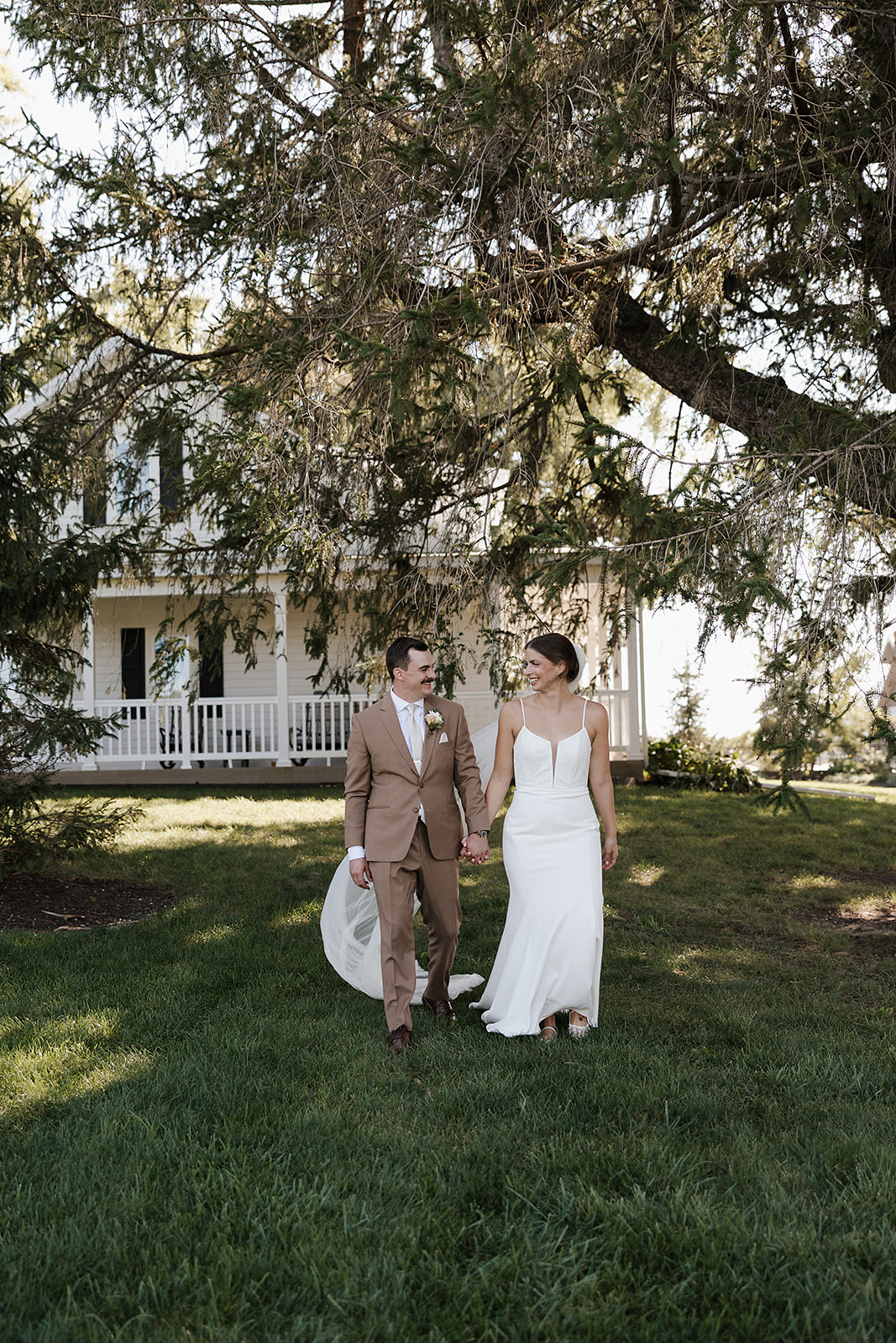 A bride and groom walking in a field in front of lilac acres