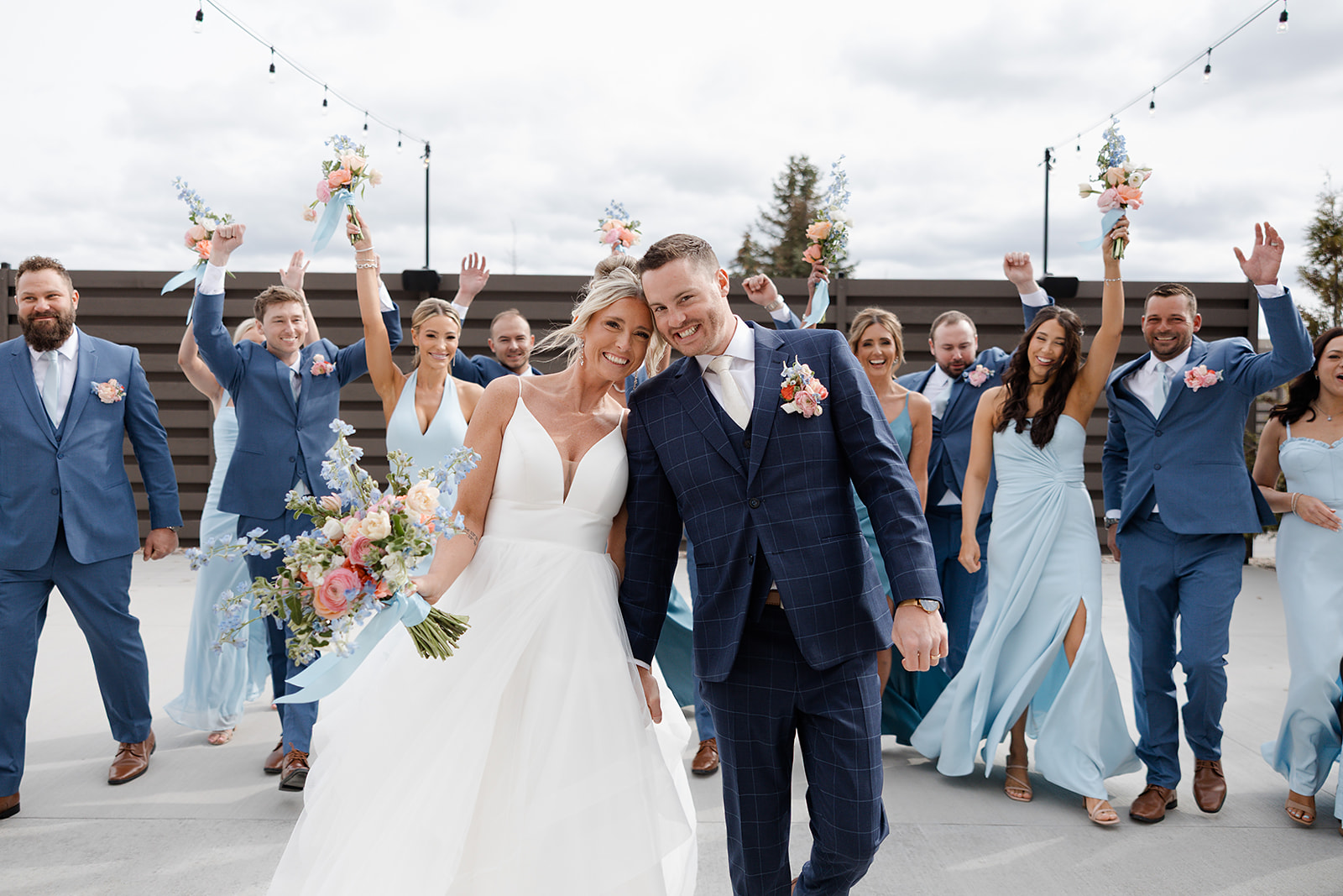 A bride and groom walking with their wedding party cheering behind them