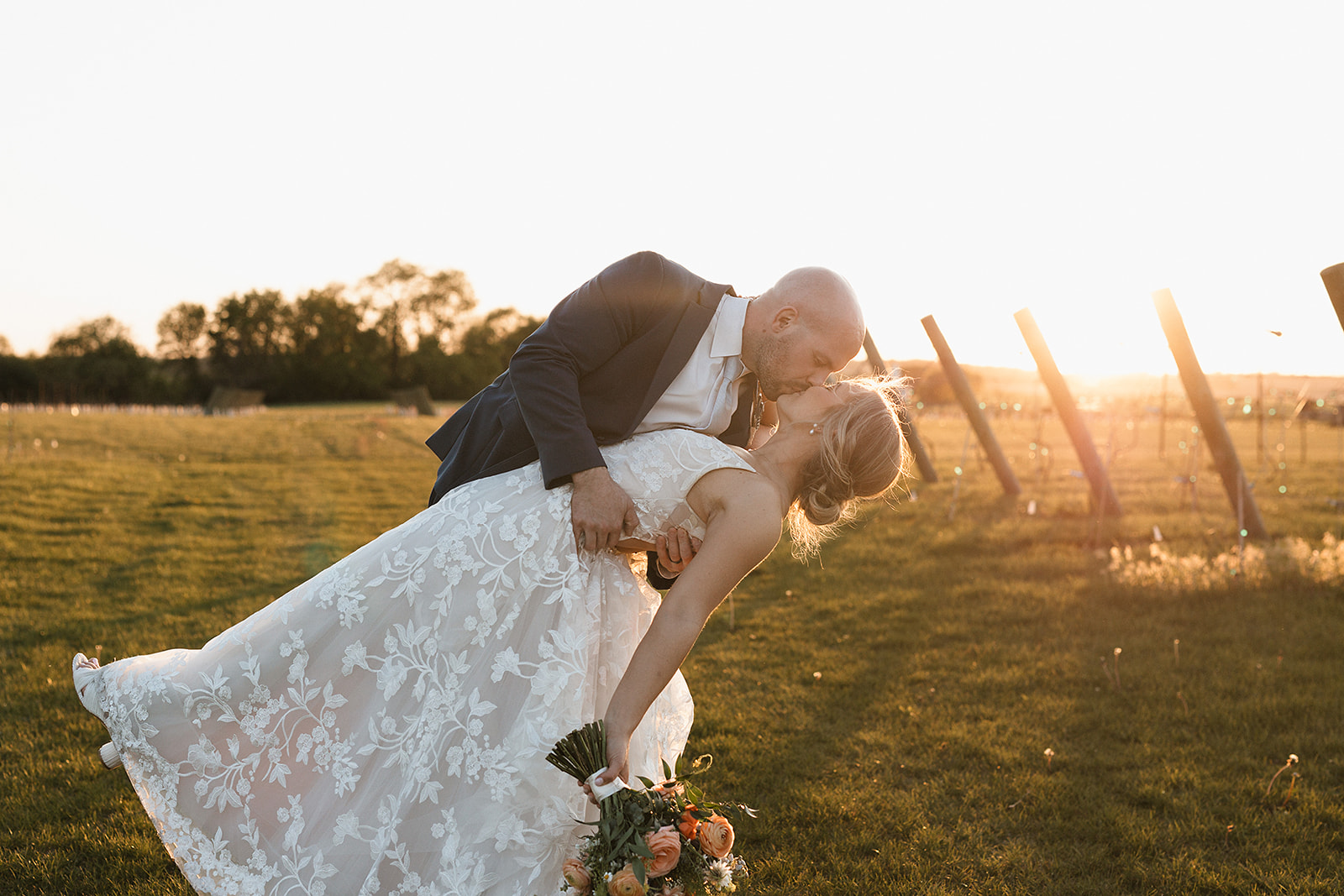 A groom dipping his bride during the sunset photo section of the wedding reception timeline