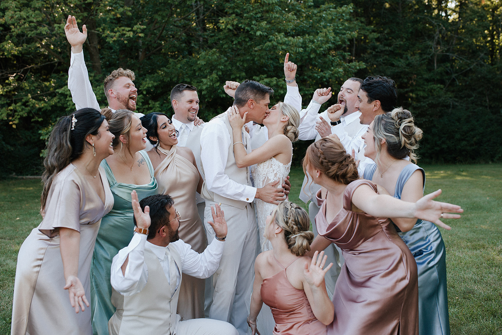 A wedding party cheering as the bride and groom kiss