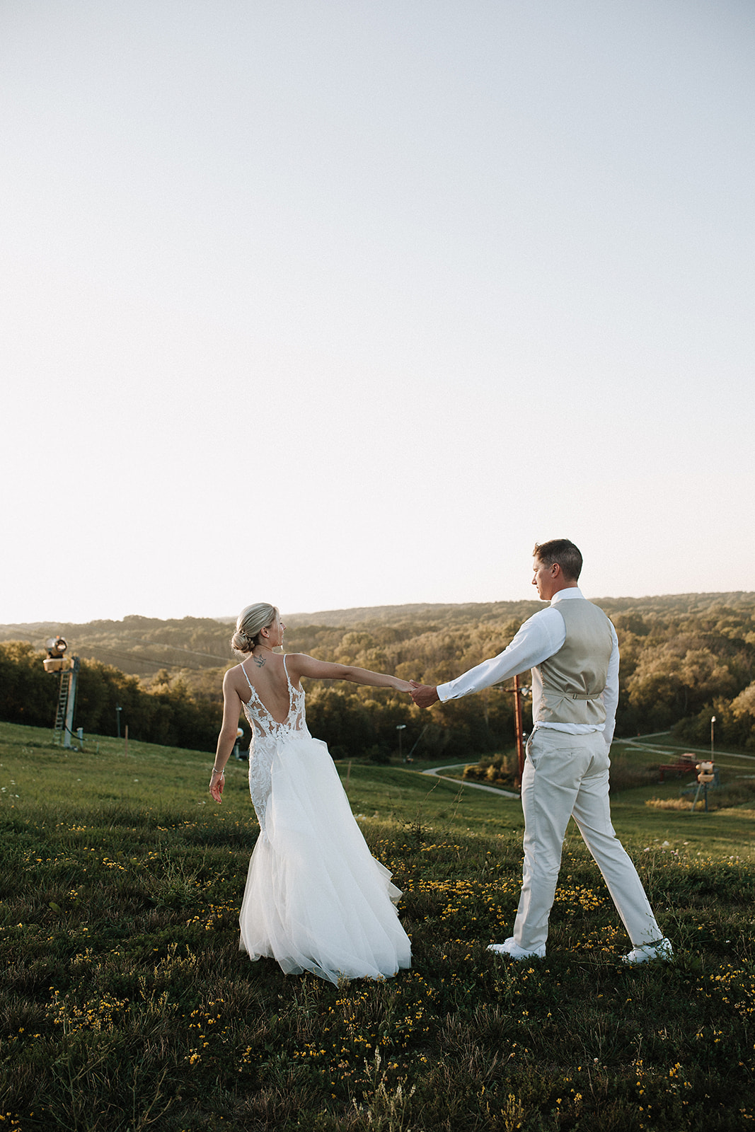 A bride and groom walking on a hill during sunset wedding photos taken by a Milwaukee wedding photographer