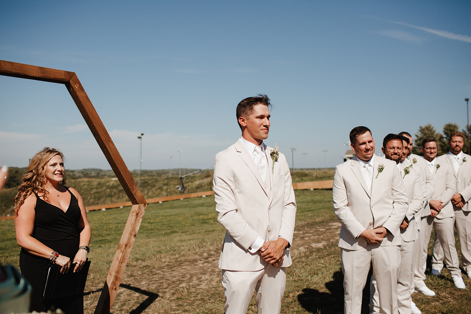 A groom watching a bride walk down the aisle in a candid photo taken by a Milwaukee wedding photographer