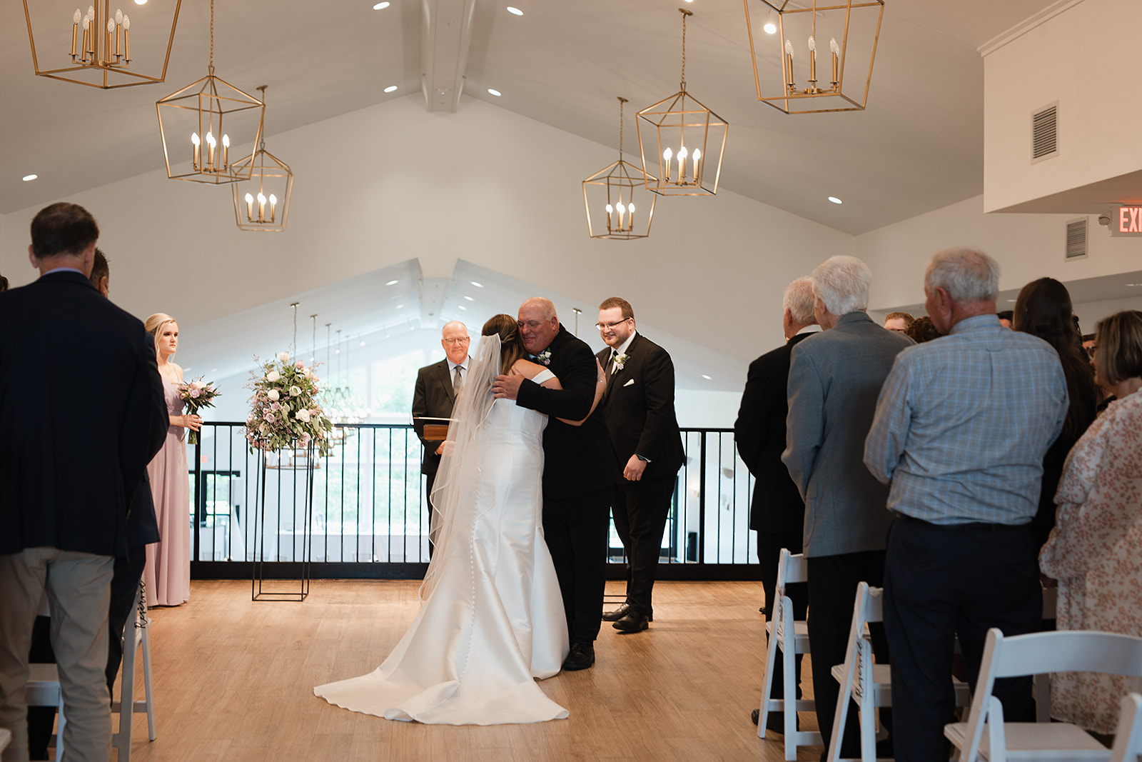 A dad hugging his daughter at the end of the wedding aisle