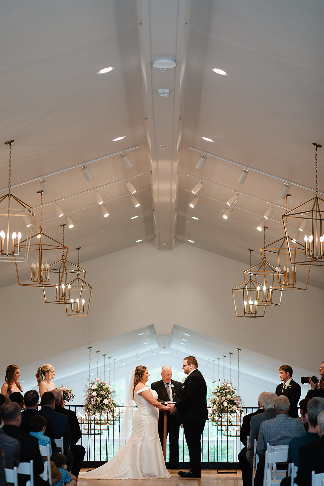 An indoor wedding ceremony taking place under chandeliers