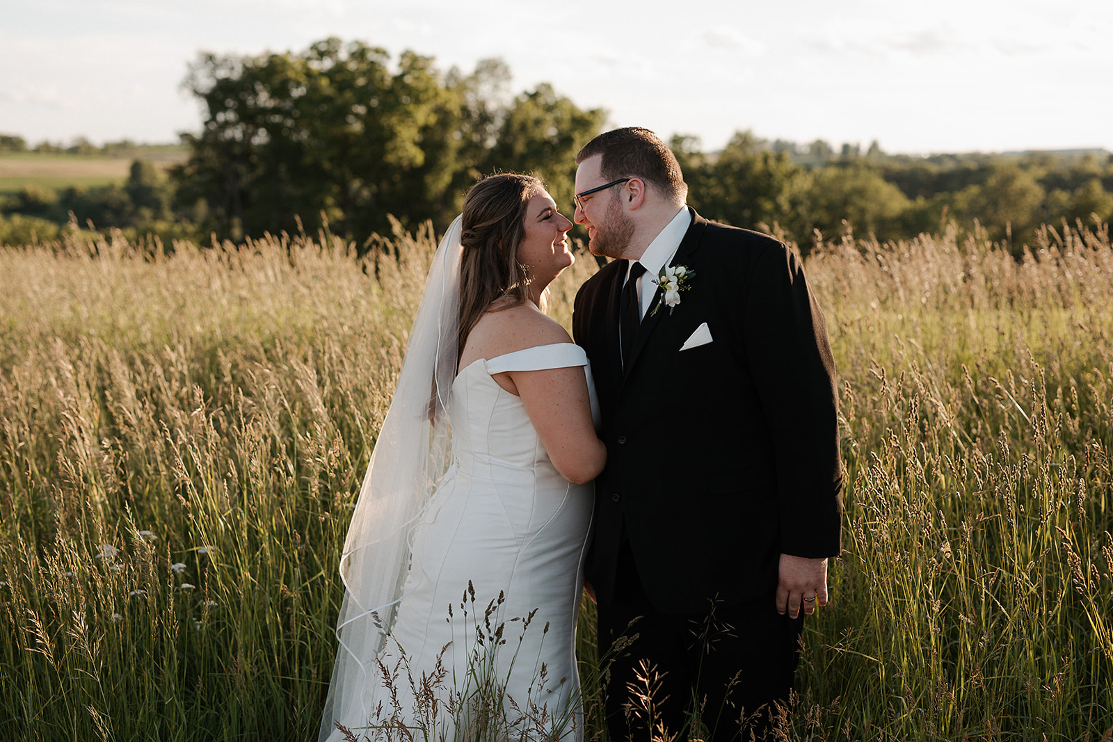 A bride and groom in a field taking wedding photos