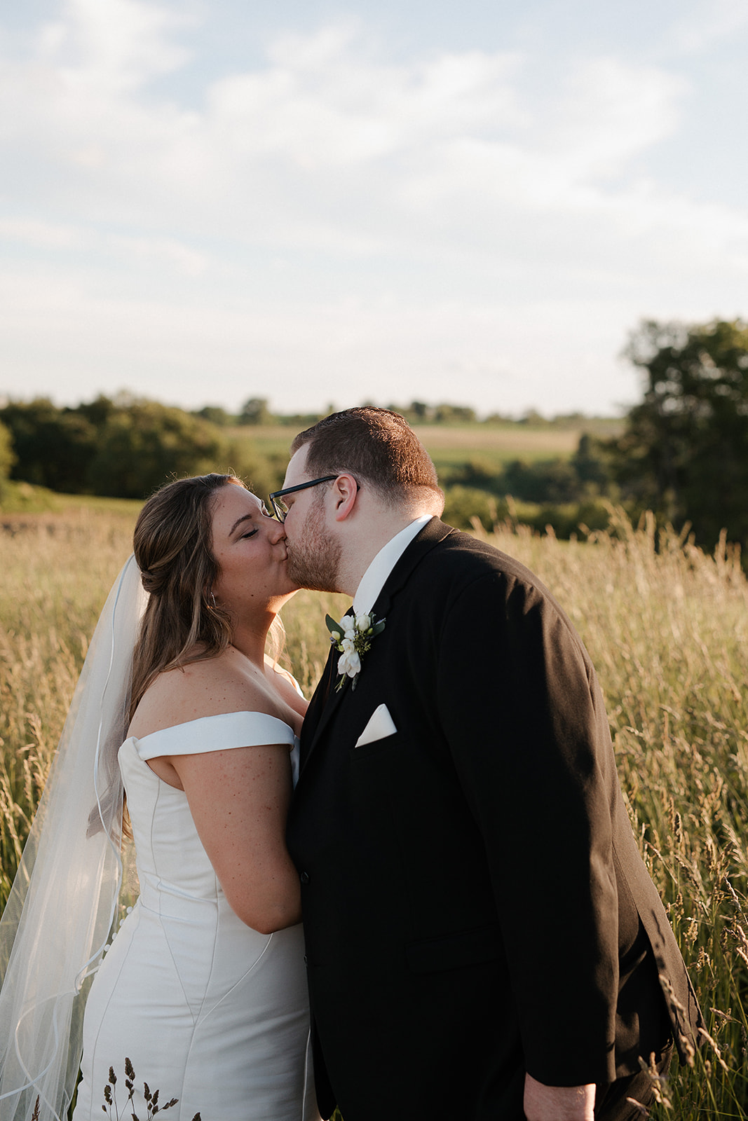 A bride and groom taking wedding sunset photos in a field