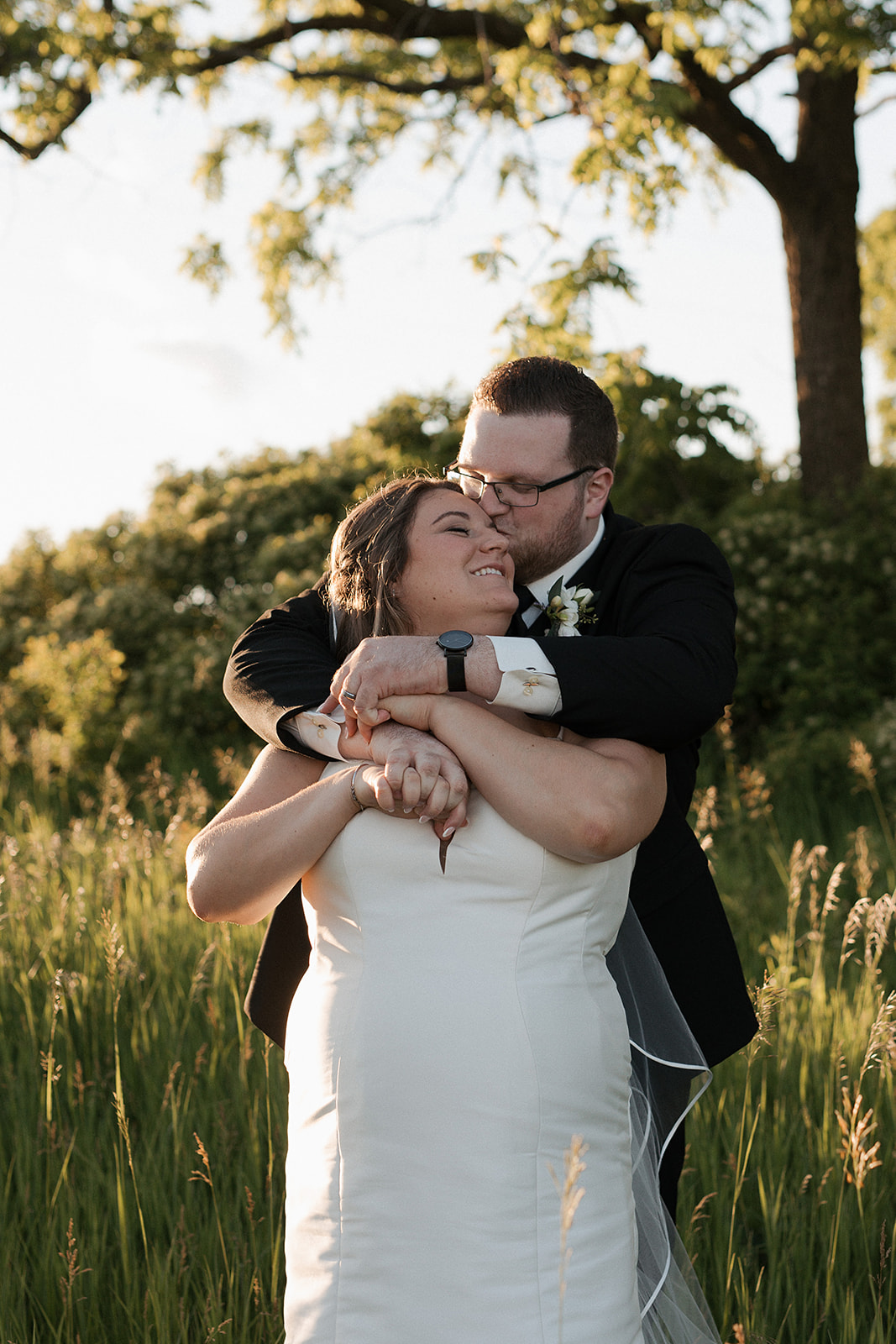 A bride and groom taking wedding sunset photos in a field