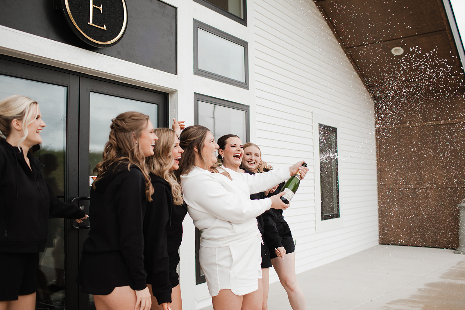 A bridal party popping champagne while getting ready for a wedding
