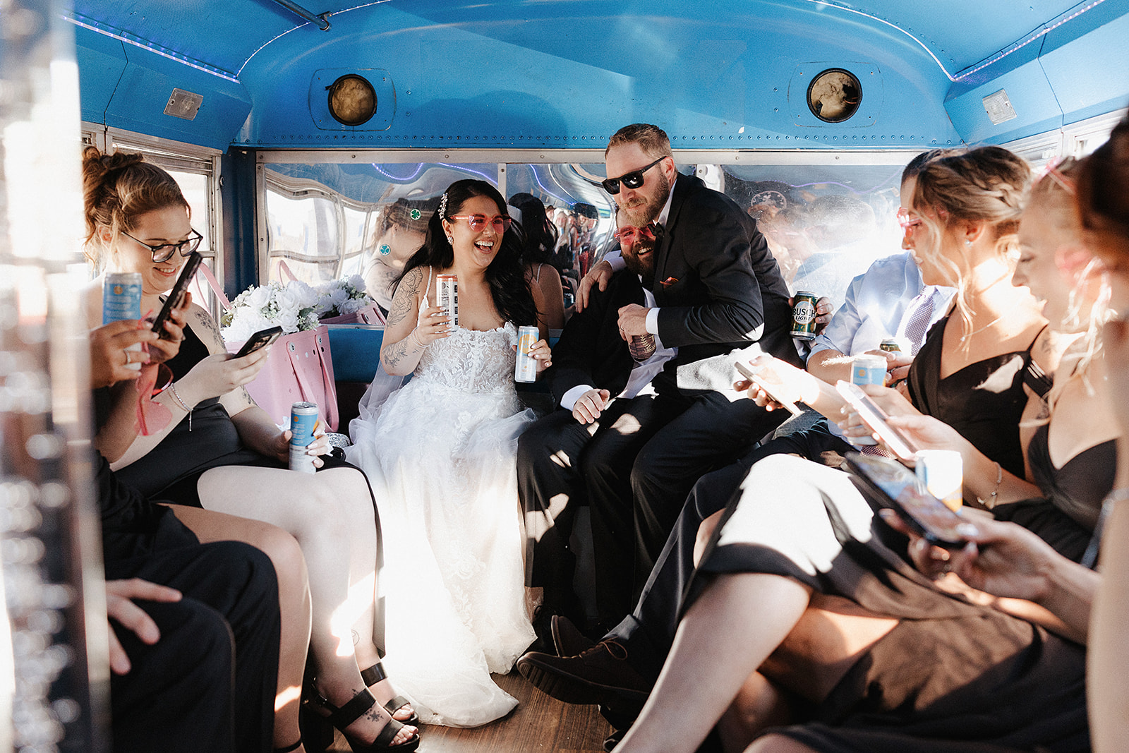 Bride and groom riding bus with guests celebrating