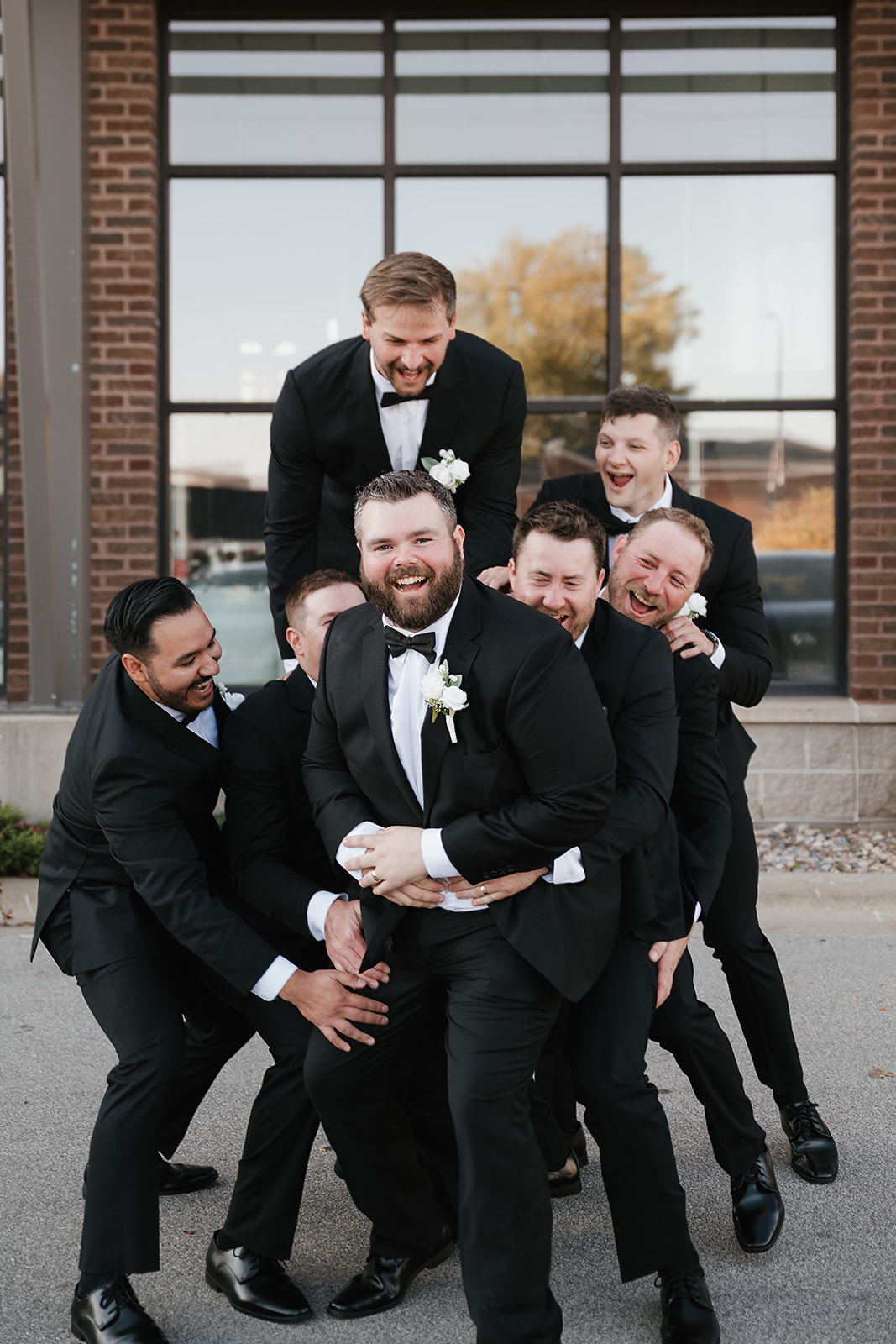 Groomsmen lifting groom playfully at the Green Bay wedding venue