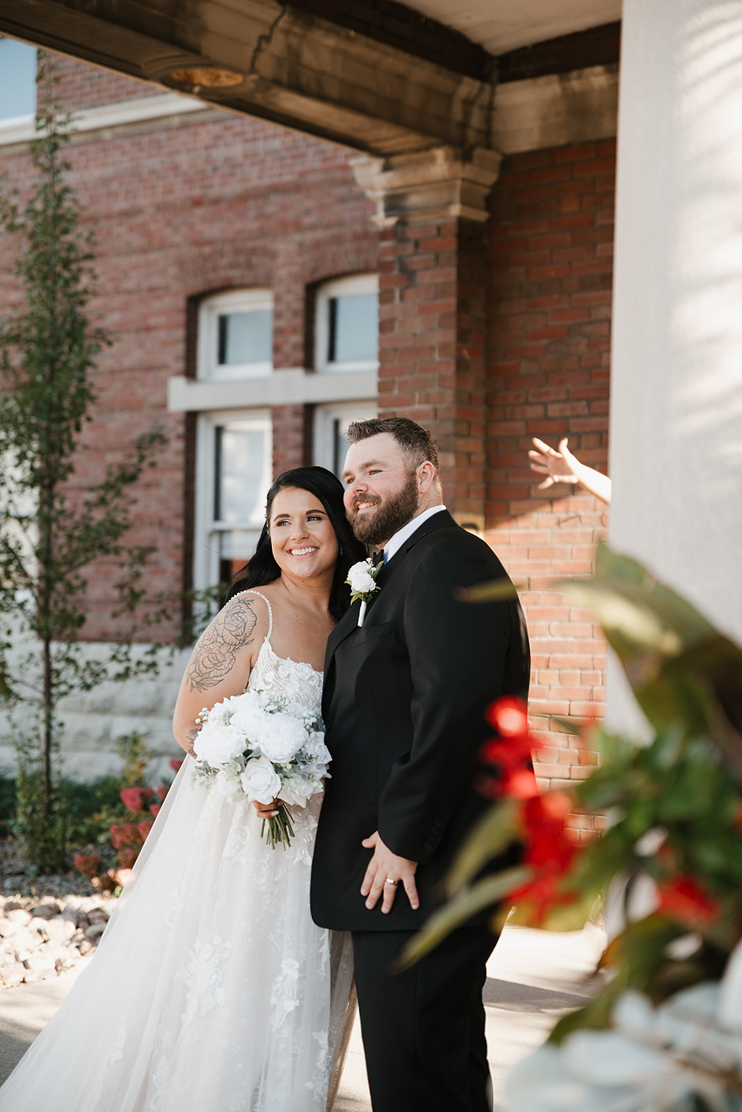 Bride and groom posing together near brick building