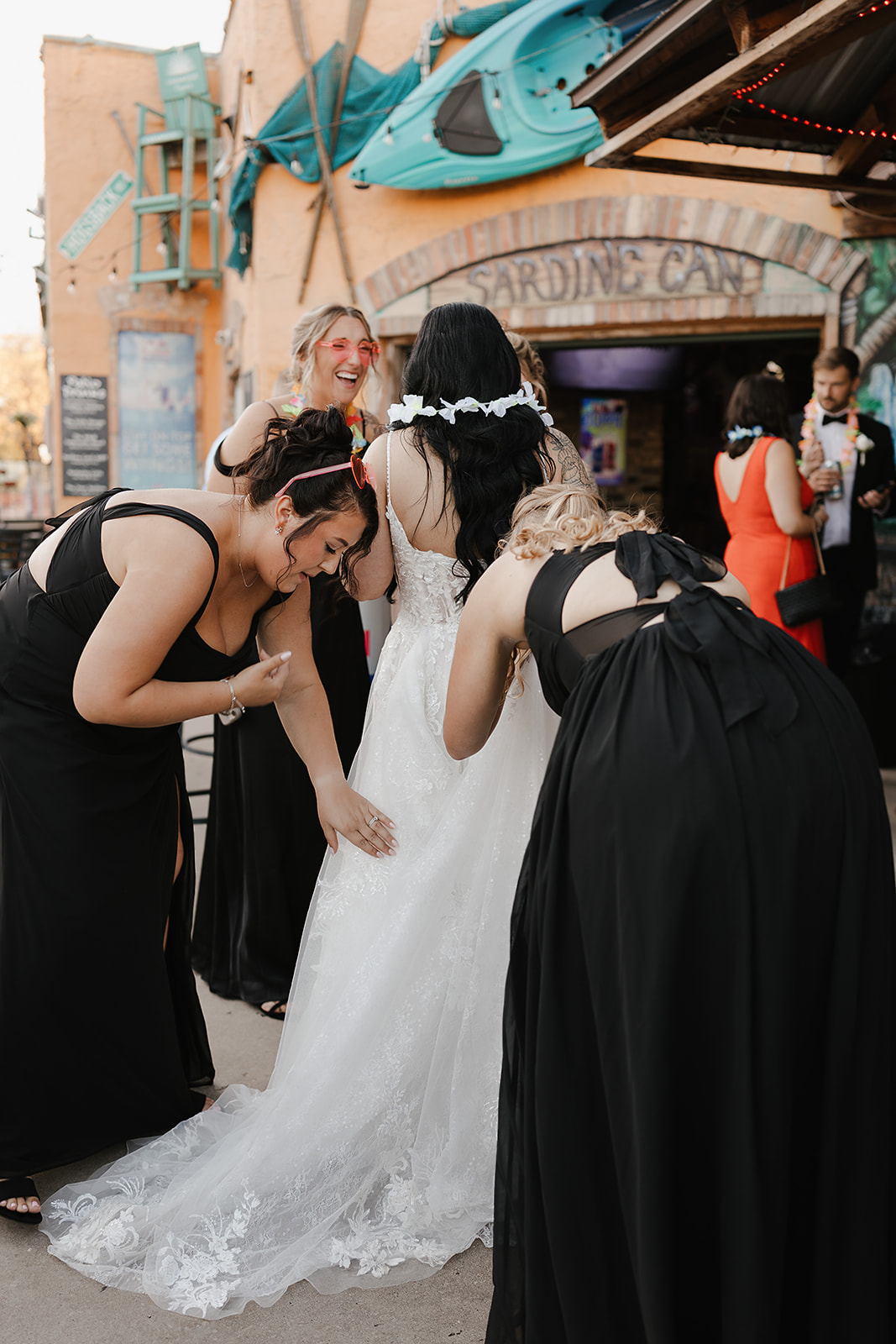 Bride adjusting veil while guests celebrate nearby