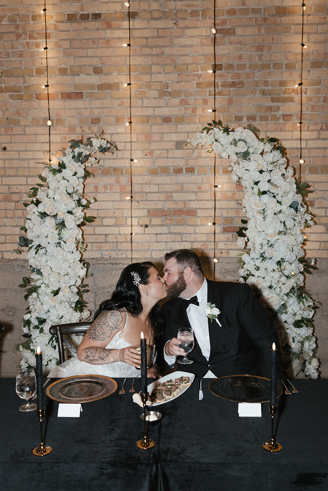 Kiss beneath floral arch at Green Bay wedding venue